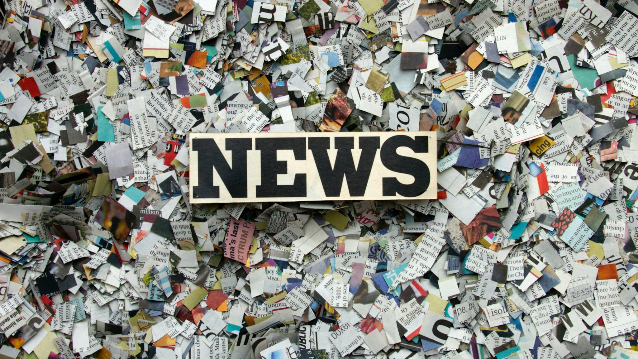 “NEWS” on block over shredded paper.