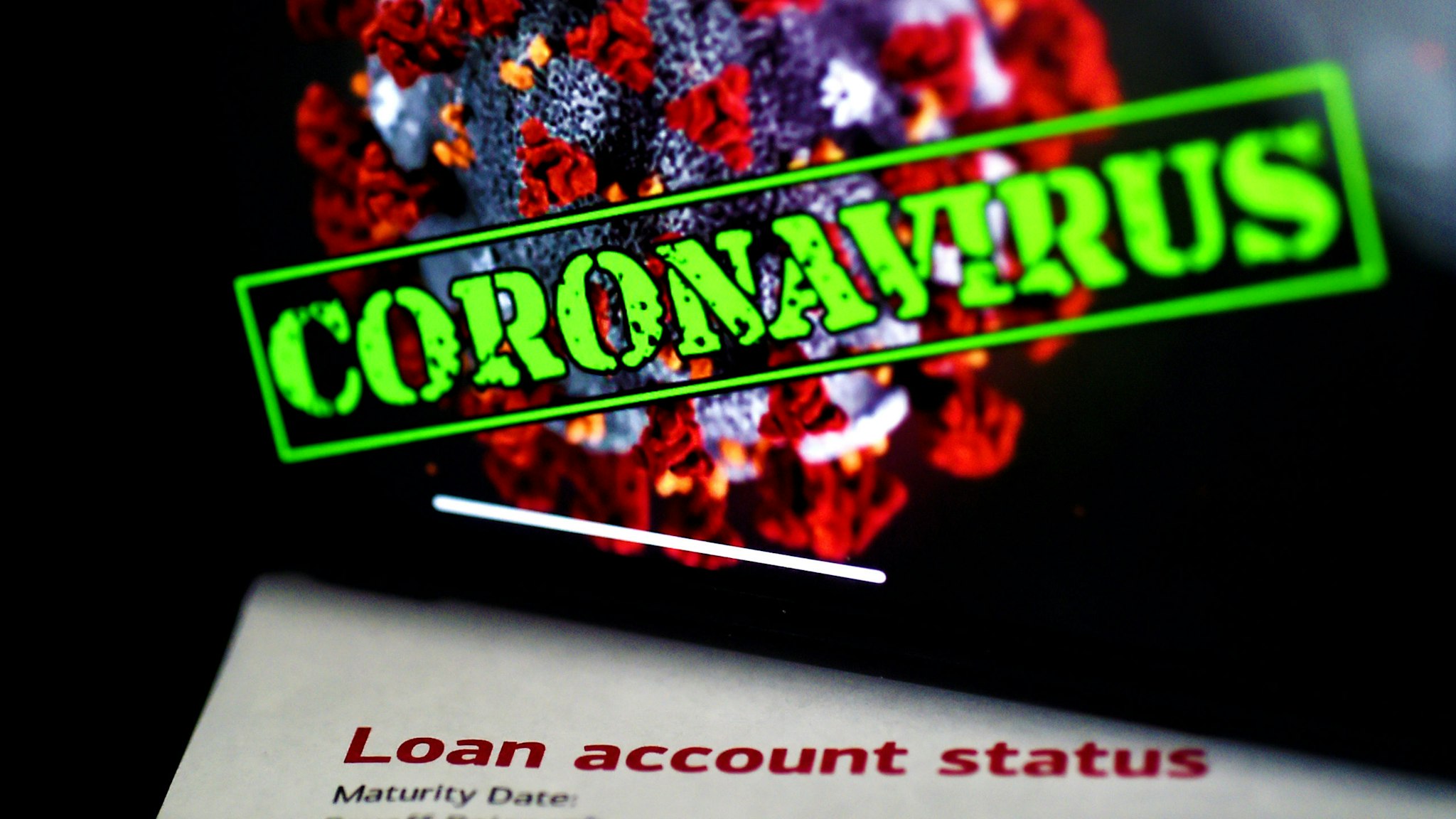 In this photo illustration, a loan statement account status is displayed next a iPhone screen behind reading "coronavirus" on April 16, 2020, in Arlington, Virginia. - The $349 billion cap for small business loans for the coronavirus stimulus was reached on April 16, 2020, taking less than two weeks to run out.