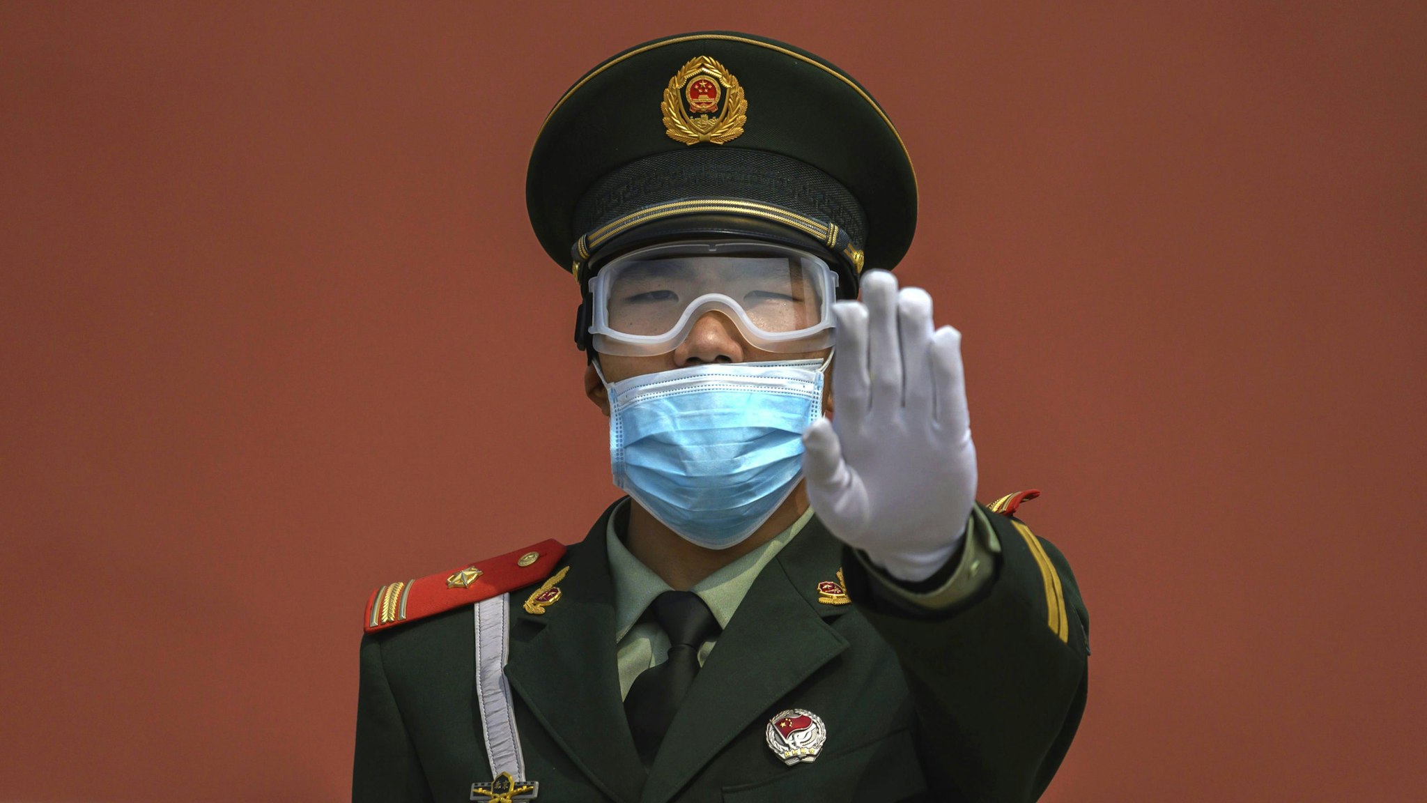 BEIJING, CHINA - MAY 01: A Chinese paramilitary police officer gestures as he wears a protective mask while standing guard at the entrance to the Forbidden City as it re-opened to limited visitors for the May holiday, on May 1, 2020 in Beijing, China. Beijing lowered its risk level after more than three months Thursday in advance of the May holiday, allowing most domestic travellers arriving in the city to do so without having to do 14 days quarantine. The Forbidden City opened to a limited number of visitors Friday morning for the first time in more than three months. After decades of growth, officials said China's economy had shrunk in the latest quarter due to the impact of the coronavirus epidemic. The slump in the worlds second largest economy is regarded as a sign of difficult times ahead for the global economy. While industrial sectors in China are showing signs of reviving production, a majority of private companies are operating at only 50% capacity, according to analysts. With the pandemic hitting hard across the world, officially the number of coronavirus cases in China is dwindling, ever since the government imposed sweeping measures to keep the disease from spreading. Officials believe the worst appears to be over in China, though there are concerns of another wave of infections as the government attempts to reboot the worlds second largest economy. Since January, China has recorded more than 81,000 cases of COVID-19 and at least 3200 deaths, mostly in and around the city of Wuhan, in central Hubei province, where the outbreak first started.