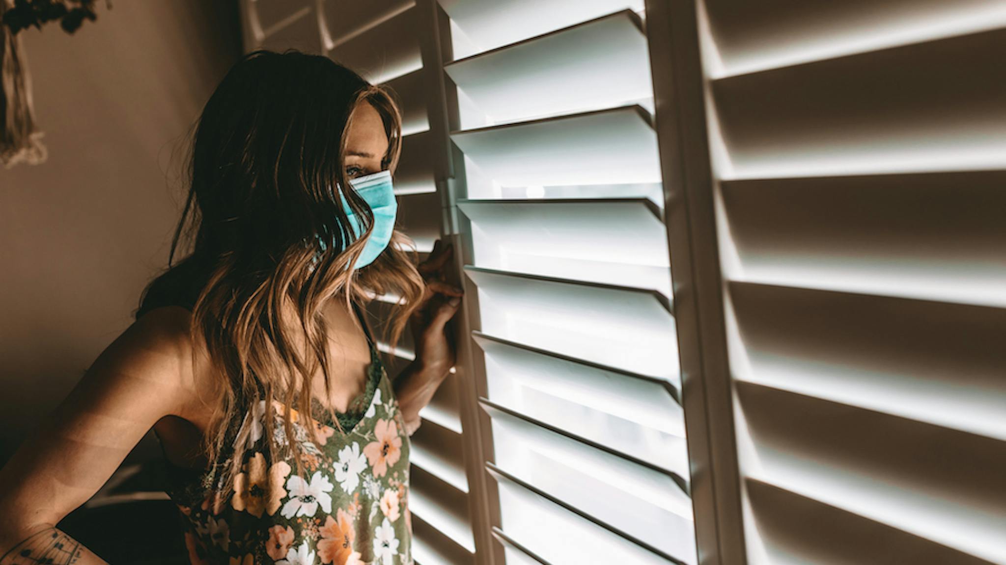 Living life at home during COVID-19 Woman with face mask in her home during stay at home order. Cleaning, and longing to get outside. COVID-19. March 2020