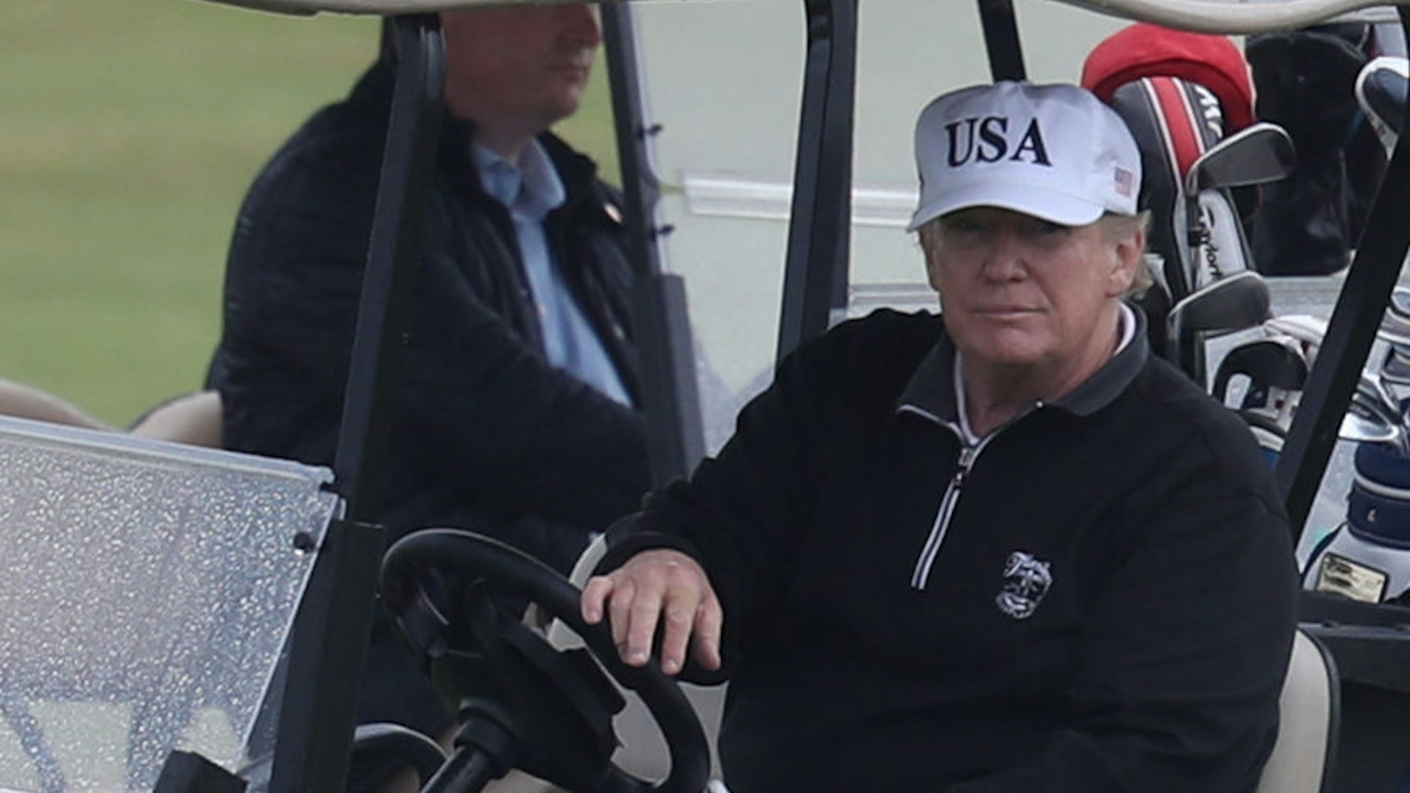 US President Donald Trump drives a golf buggy on his golf course at the Trump Turnberry resort in South Ayrshire, where he and his wife Melania, spent the weekend as part of their visit to the UK before leaving for Finland where he will meet Russian leader Vladimir Putin for talks on Monday. (Photo by Andrew Milligan/PA Images via Getty Images)