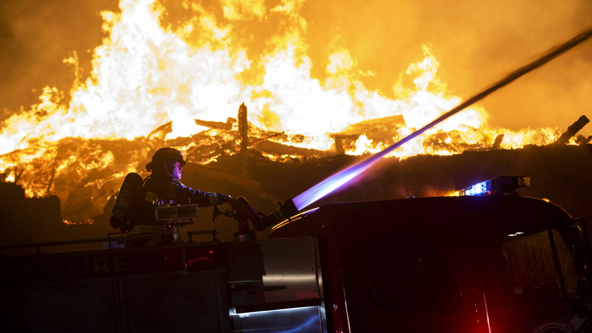 MINNEAPOLIS, MN - MAY 27: Fire fighters work to put out a fire at a factory near the Third Police Precinct on May 27, 2020 in Minneapolis, Minnesota. A number of businesses and homes were damaged as the area has become the site of an ongoing protest after the police killing of George Floyd. Four Minneapolis police officers have been fired after a video taken by a bystander was posted on social media showing Floyd's neck being pinned to the ground by an officer as he repeatedly said, "I can’t breathe". Floyd was later pronounced dead while in police custody after being transported to Hennepin County Medical Center.
