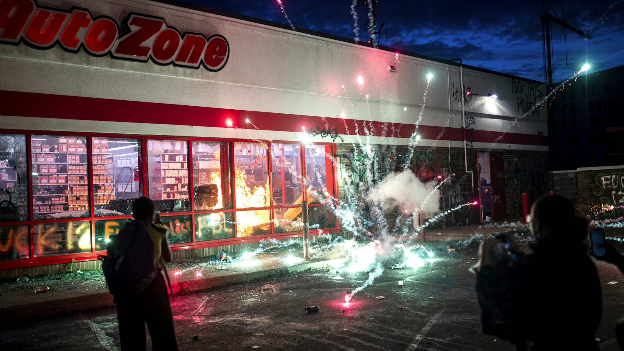 MINNEAPOLIS, MN - MAY 27: A firework explodes as a fire burns inside of an Auto Zone store near the 3rd Police Precinct on May 27, 2020 in Minneapolis, Minnesota. Businesses near the station were looted and damaged today as the area has become the site of an ongoing protest after the police killing of George Floyd. Four Minneapolis police officers have been fired after a video taken by a bystander was posted on social media showing Floyd's neck being pinned to the ground by an officer as he repeatedly said, "I can’t breathe". Floyd was later pronounced dead while in police custody after being transported to Hennepin County Medical Center.