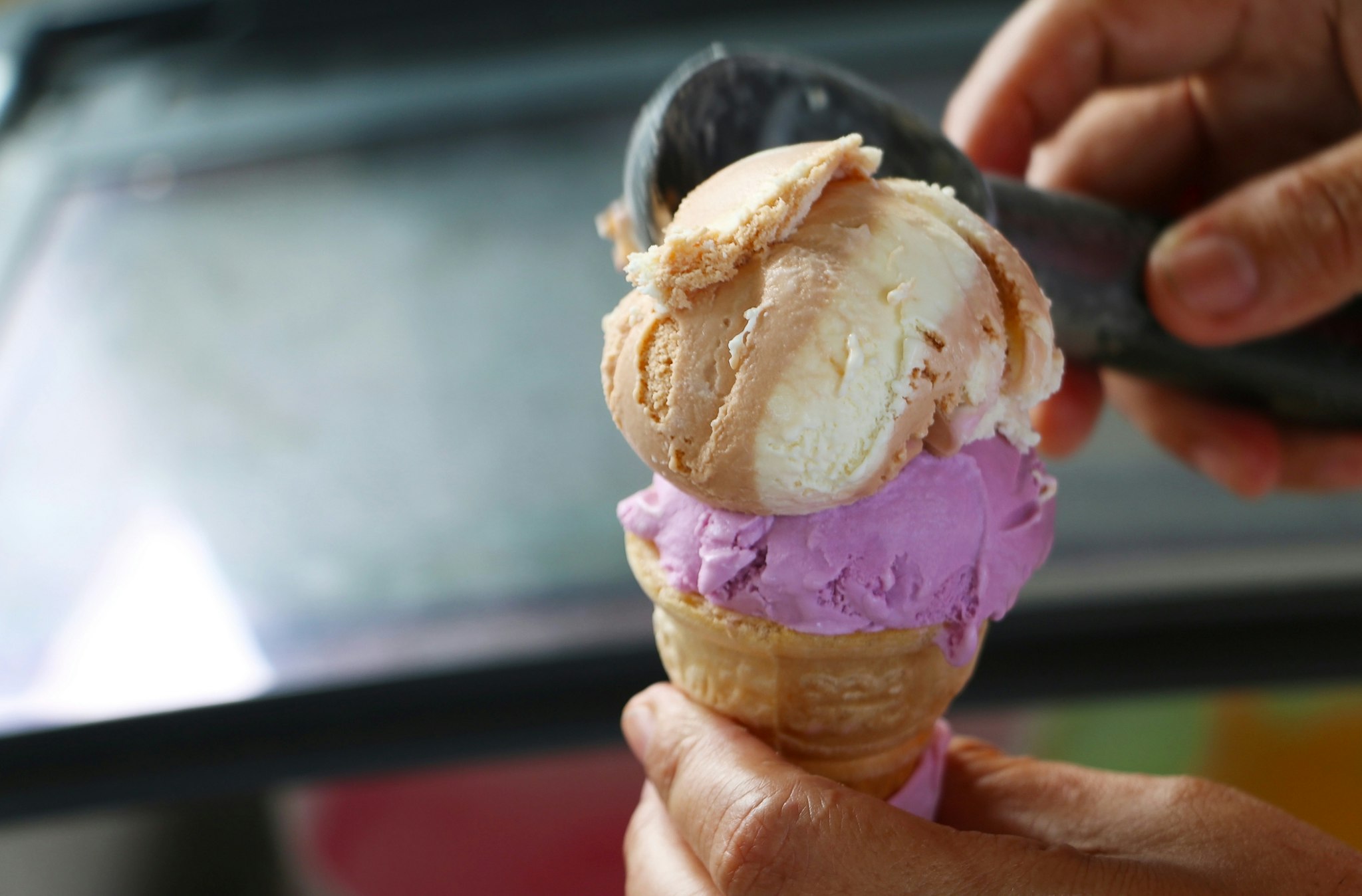 Crop hand scooped ice cream into ice cream cone