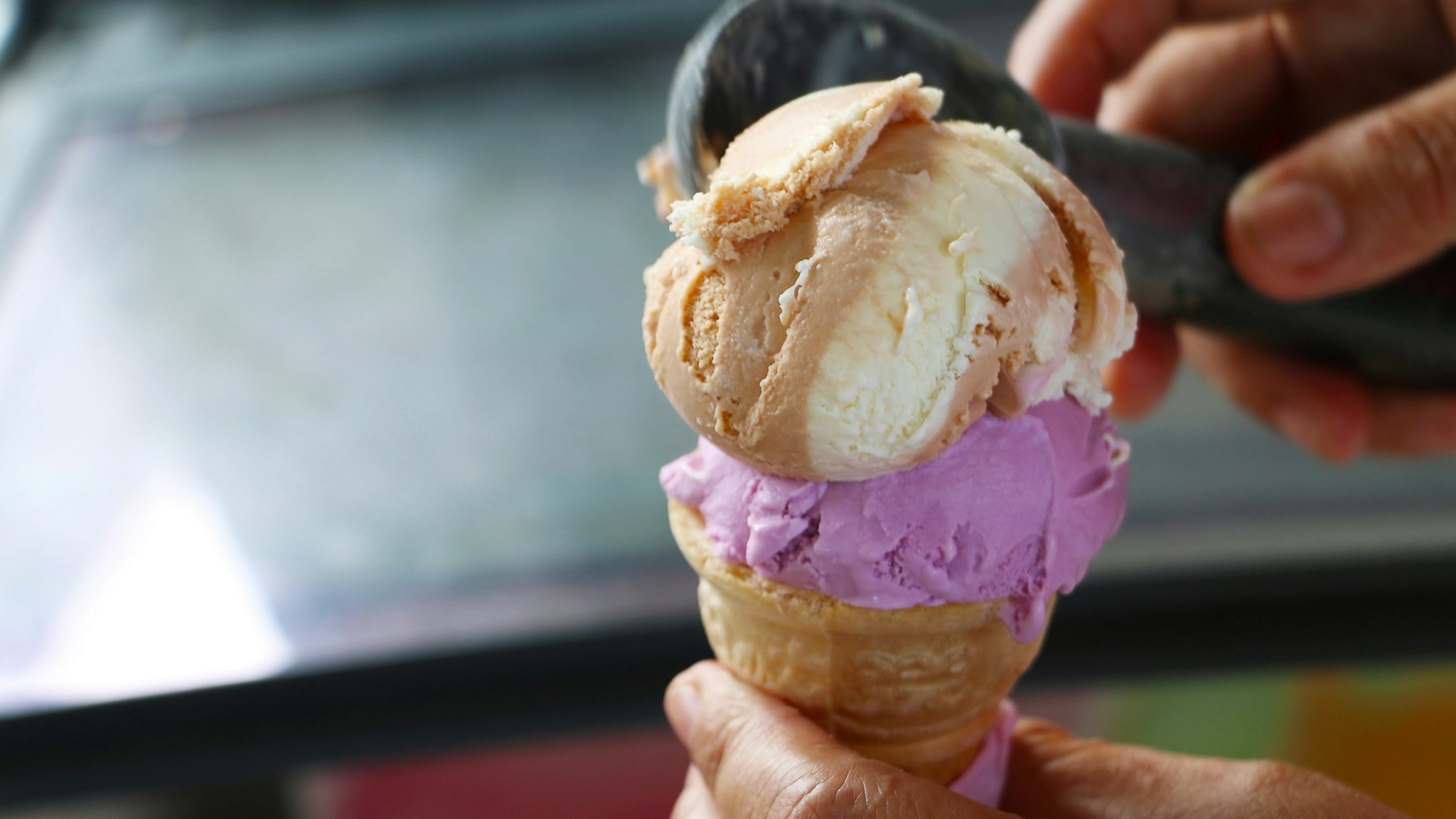 Crop hand scooped ice cream into ice cream cone