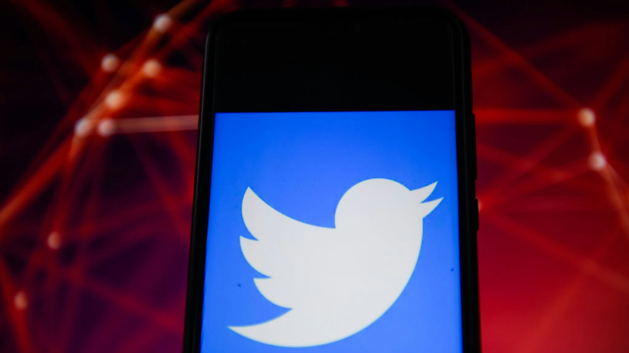 In this photo illustration a Twitter logo seen displayed on a smartphone.