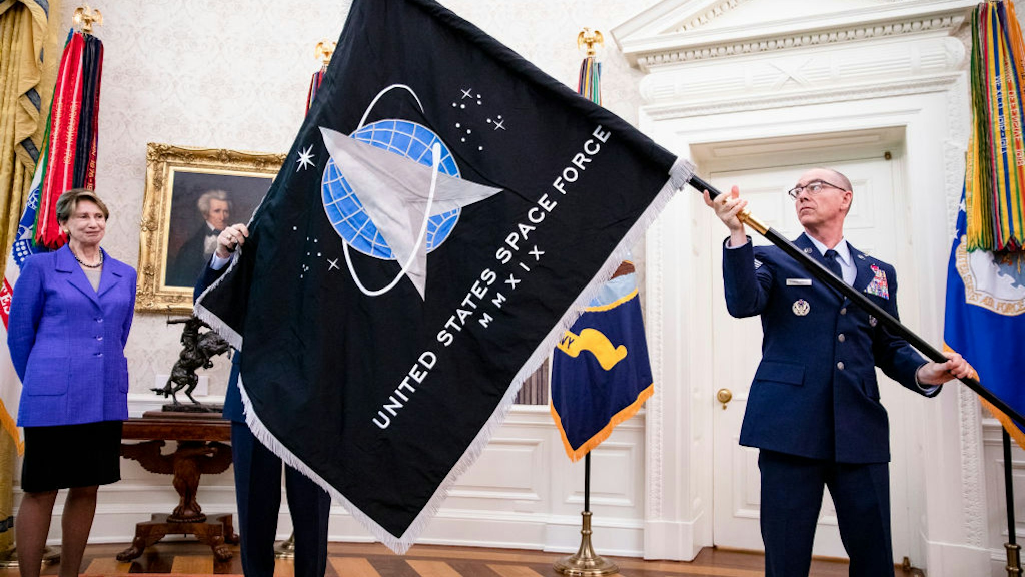 Gen. Jay Raymond (R), Chief of Space Operations, and CMSgt Roger Towberman (L), with Secretary of the Air Force Barbara Barrett present US President Donald Trump with the official flag of the United States Space Force in the Oval Office of the White House in Washington, DC on May 15, 2020.