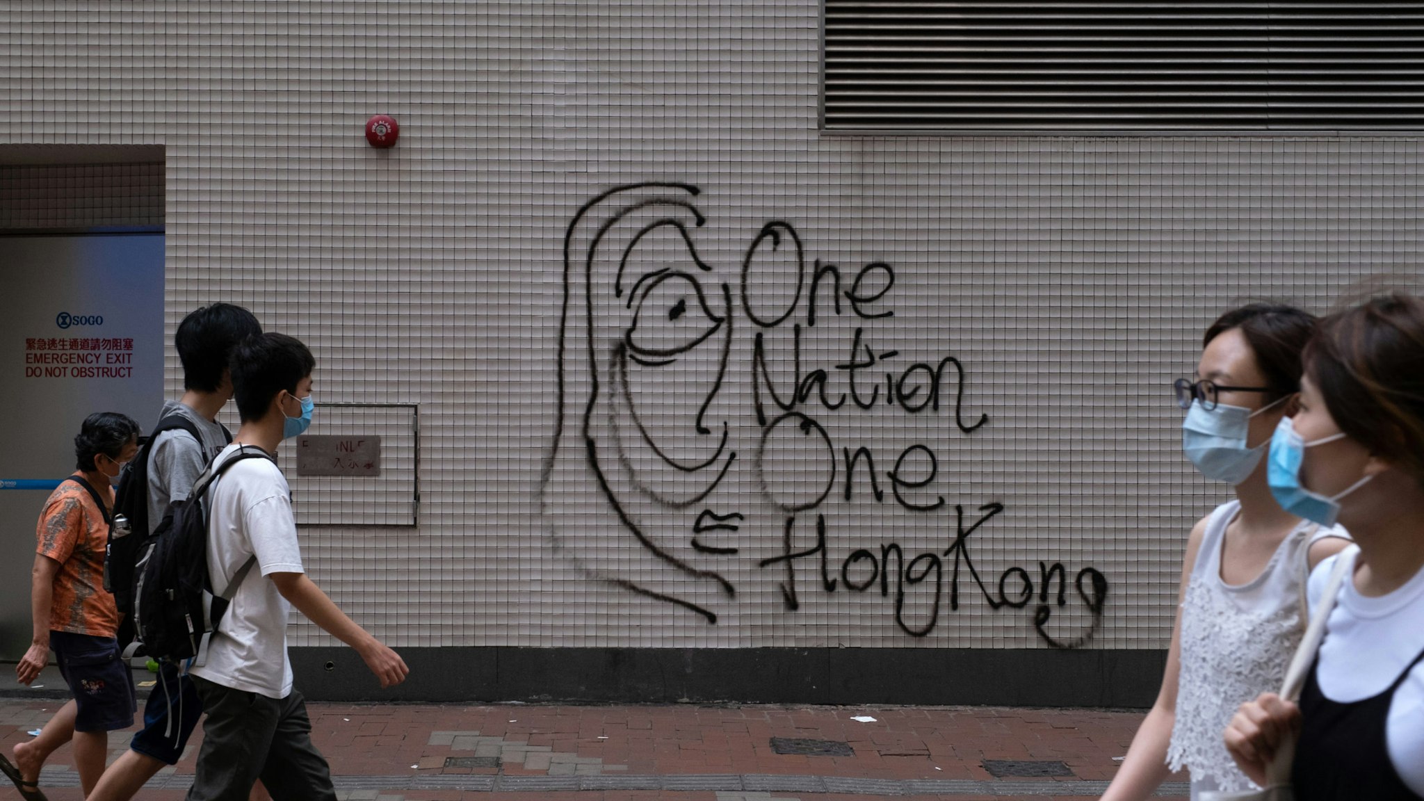 Graffiti reading "One Nation, One Hong Kong" is marked on a wall during a protest against a planned national security law in the Causeway Bay district in Hong Kong, China, on Sunday, May 24, 2020. Almost 200 politicians and legislators from 23 countries issued a joint statement criticizing Chinas plans to impose a sweeping national security law in Hong Kong, and warned that it could spark more protests in the city, Radio and Television Hong Kong reported. Photographer: Roy Liu/Bloomberg via Getty Images