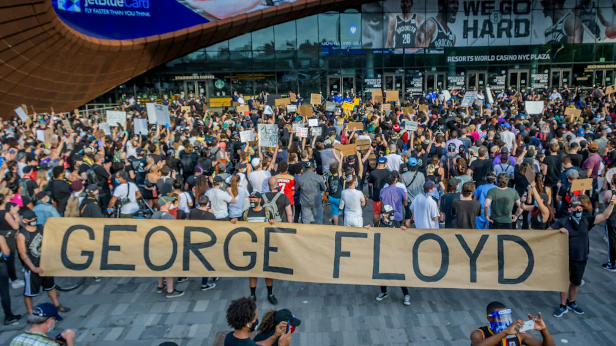 Protesters holding a giant banner reading GEORGE FLOYD outside the Barclays Center. Hundreds of protesters made their way toward Barclays Center in Brooklyn to demonstrate against police brutality in the wake of George Floyd's death while in police custody in Minneapolis.