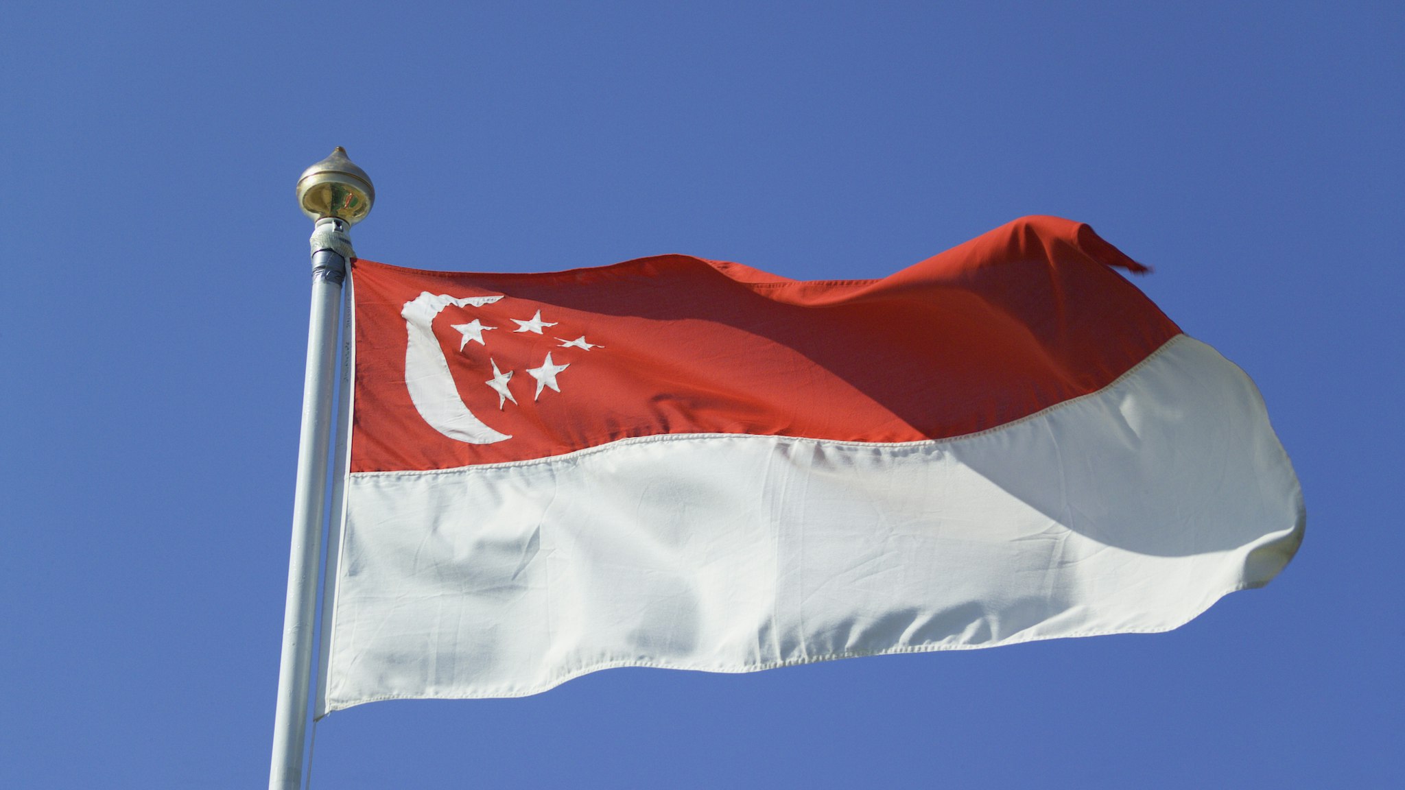 Close up of singaporean flag against blue sky, low angle view - stock photo