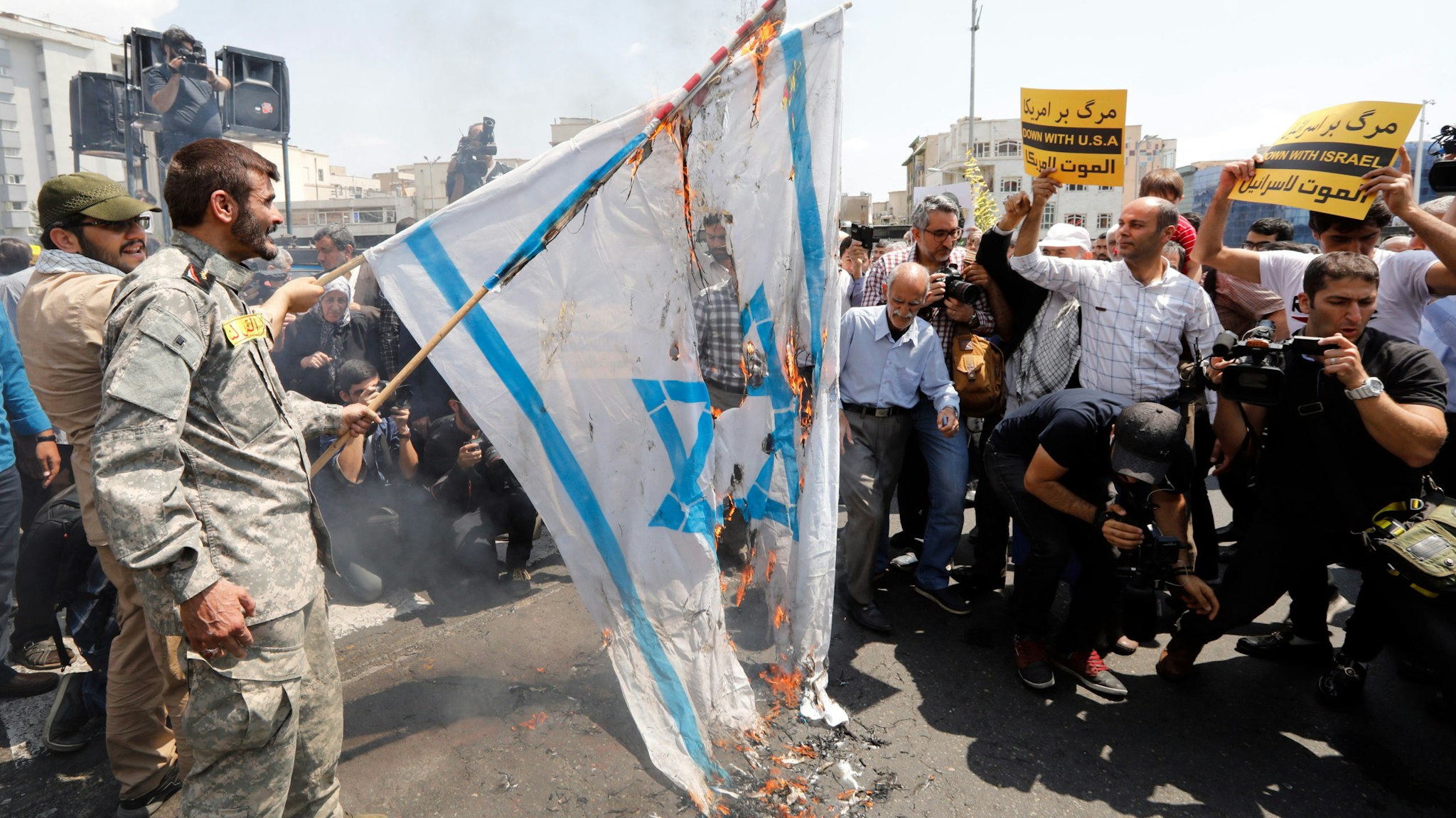 Iranians burn a US and an Israeli flag as they take part in an anti-US and Israel demonstration after weekly Friday prayers in the capital Tehran on May 18, 2018, to show their solidarity with Palestinians over recent violent events in Gaza. The banners read in Farsi "death to America".