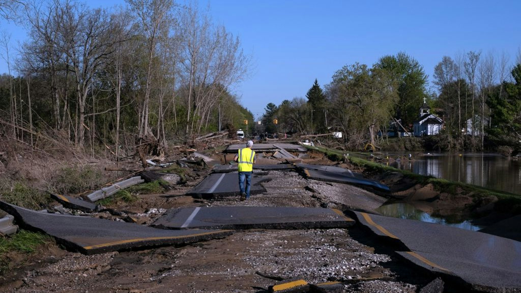 TOPSHOT - A man walks across a washed out West Saginaw Road in Sanford, Michigan, on May 21,2020, after the area saw heavy flooding and damage from heavy rains throughout central Michigan . - More than 10,000 residents were evacuating their homes in Michigan on May 20, 2020 after two dams failed following heavy rains triggered what officials warned will be historic flooding. Governor Gretchen Whitmer declared a state of emergency in Midland County, site of the breached dams, in the towns of Edenville and Sanford. (Photo by SETH HERALD / AFP) (Photo by SETH HERALD/AFP via Getty Images)