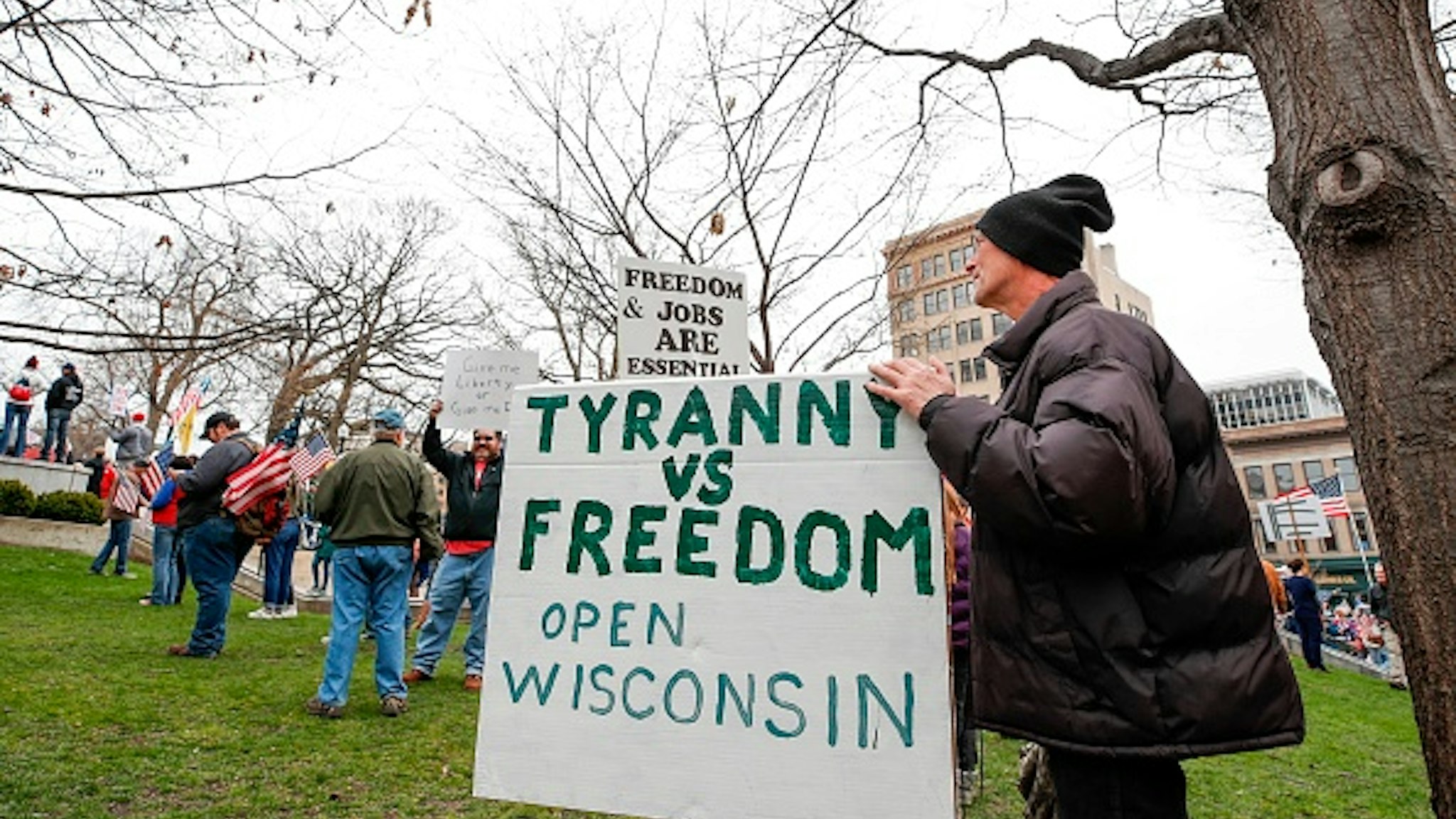 A man holsd sign during a protest against the coronavirus shutdown in front of State Capitol in Madison, Wisconsin, on April 24, 2020. - Gyms, hair salons and tattoo parlors had a green light to reopen in the US state of Georgia on Friday as the death toll from the coronavirus pandemic soared past 50,000 in the US.