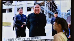 TOPSHOT-SKOREA-NKorea-politics-Kim-diplomacy TOPSHOT - A woman walks past a television news screen showing a picture of North Korean leader Kim Jong Un attending a ceremony to mark the completion of Sunchon phosphatic fertiliser factory, at a railway station in Seoul on May 2, 2020. - North Korea's Kim Jong Un has made his first public appearance in nearly three weeks, state media reported on May 2, following intense speculation that the leader of the nuclear-armed nation was seriously ill or possibly dead. (Photo by Jung Yeon-je / AFP) (Photo by