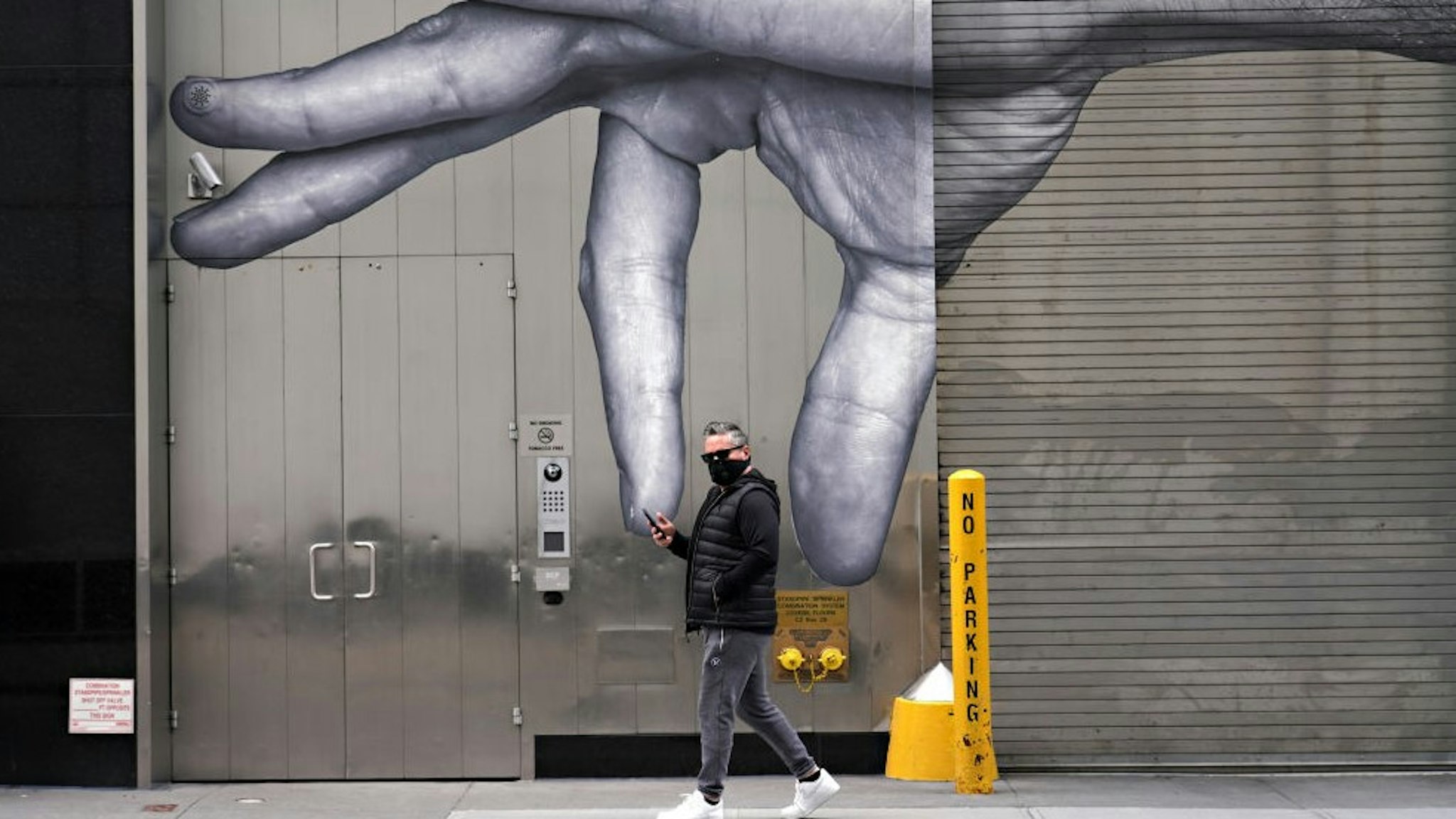 NEW YORK, NEW YORK - APRIL 05: A man wearing a protective mask walks by street art amid the coronavirus pandemic on April 05, 2020 in New York City. COVID-19 has spread to most countries around the world, claiming almost 70,000 lives with infections nearing 1.3 million people. (Photo by