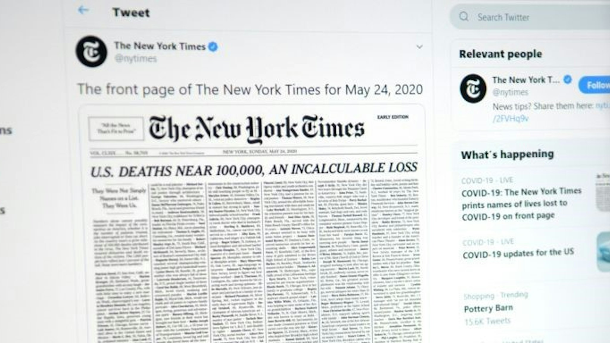 This picture taken on May 23, 2020, in Los Angeles, California, shows a woman looking at a computer screen with a tweet by the New York Times newspaper account showing the early edition front page of May 24, 2020, with a list of 1,000 names printed on it, that represents 1% of the lives lost due to the novel coronavirus pandemic, COVID-19, in the US. (Photo by Agustin PAULLIER / AFP) (Photo by