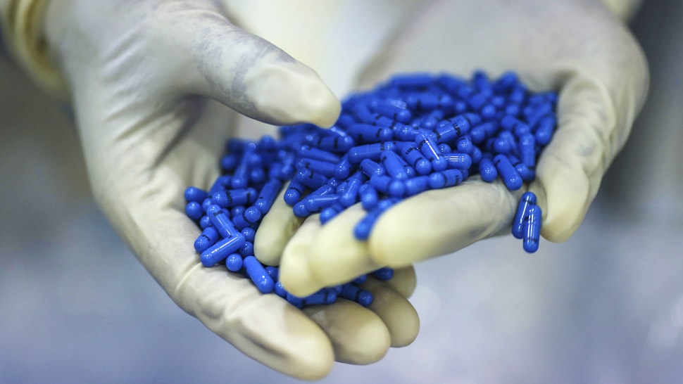 An employee holds Ramipril capsules for a photograph inside a coating unit at the Lupin Ltd. pharmaceutical plant in Salcette, Goa, India, on Friday, Feb. 7, 2014. Lupin, founded by billionaire Desh Bandhu Gupta, expects to gain share in the U.S. amid increased regulatory oversight and curbs on competitors including Ranbaxy Laboratories Ltd.