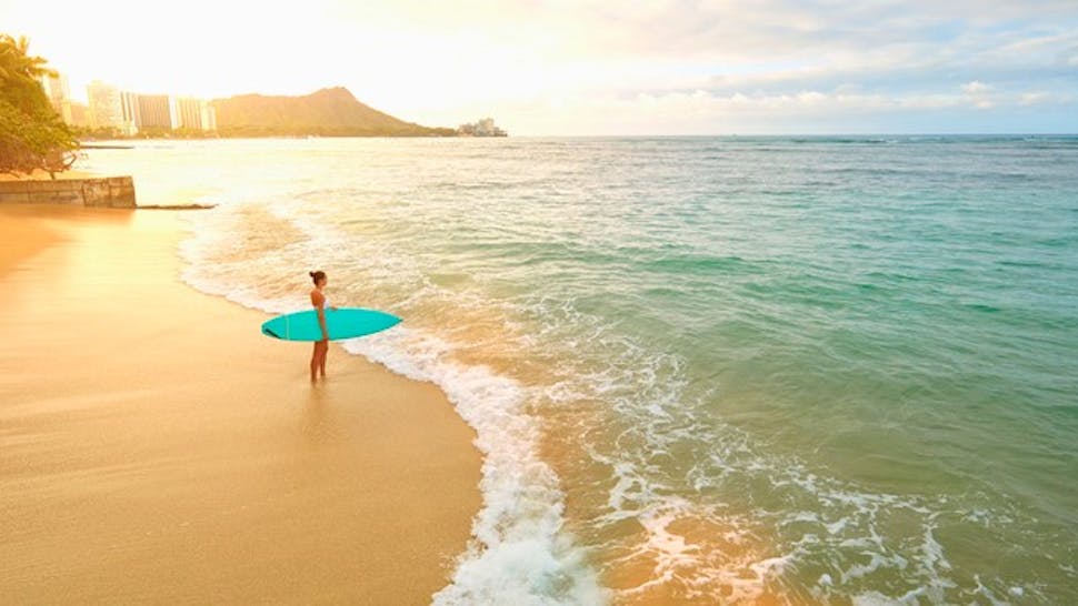 Pacific Islander woman holding surfboard on beach