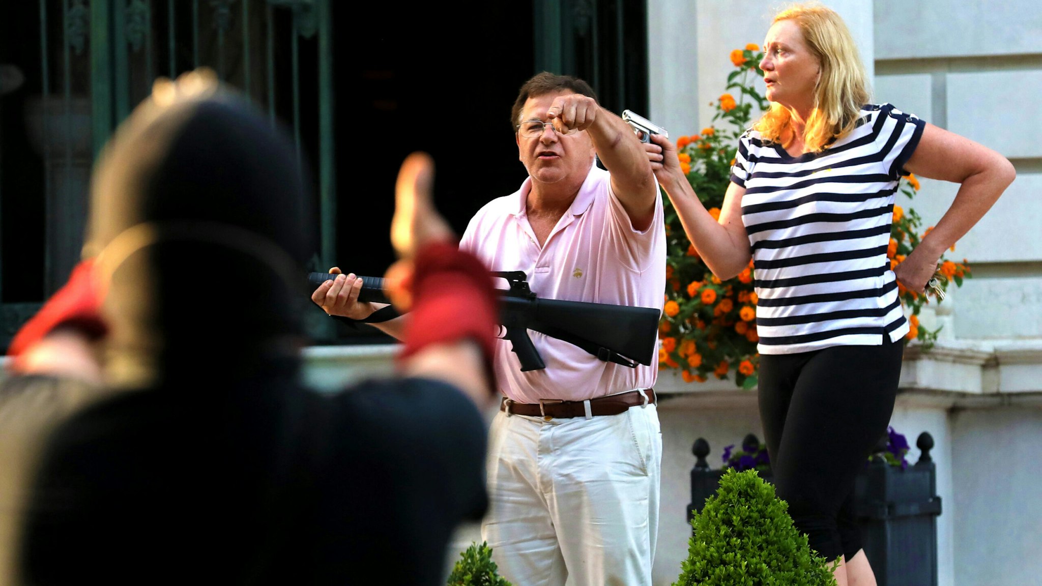 Armed homeowners standing in front of their house along Portland Place confront protesters as they march to Mayor Lyda Krewson's house on Sunday, June 28, 2020, in the Central West End in St. Louis.