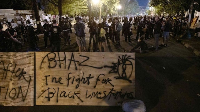 Protesters confront police near a barricade they erected and marked with the sign "Black House Autonomous Zone" in front of Lafayette Park near the White House, in Washington, DC on June 22, 2020. - A crowd of protestors tried to topple the statue of former US president General Andrew Jackson near the White House in the evening of June 22 as police responded with pepper spray to break up new demonstrations that erupted in Washington. (Photo by ROBERTO SCHMIDT / AFP)