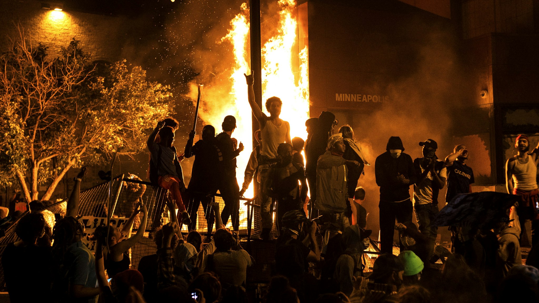 MINNEAPOLIS, MN - MAY 28: Protesters cheer as the Third Police Precinct burns behind them on May 28, 2020 in Minneapolis, Minnesota. As unrest continues after the death of George Floyd, police abandoned the precinct building, allowing protesters to set fire to it.