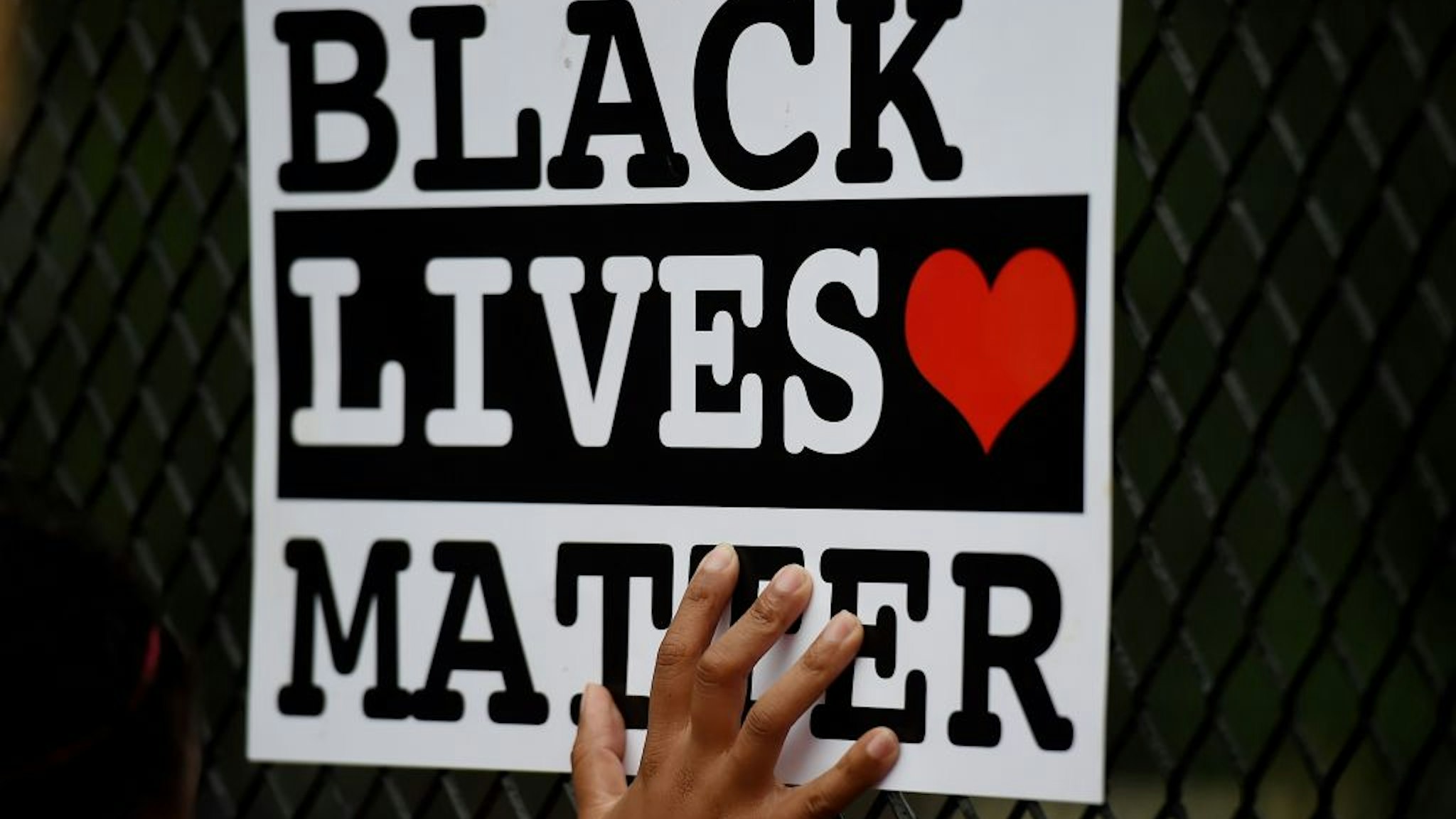 A protestor holds up a Black Lives Matter sign against a recently erected metal fence in front of Lafayette Square near the White House to keep protestors at bay on June 4, 2020 in Washington, DC. - On May 25, 2020, Floyd, a 46-year-old black man suspected of passing a counterfeit $20 bill, died in Minneapolis after Derek Chauvin, a white police officer, pressed his knee to Floyd's neck for almost nine minutes. (Photo by Olivier DOULIERY / AFP) (Photo by OLIVIER DOULIERY/AFP via Getty Images)