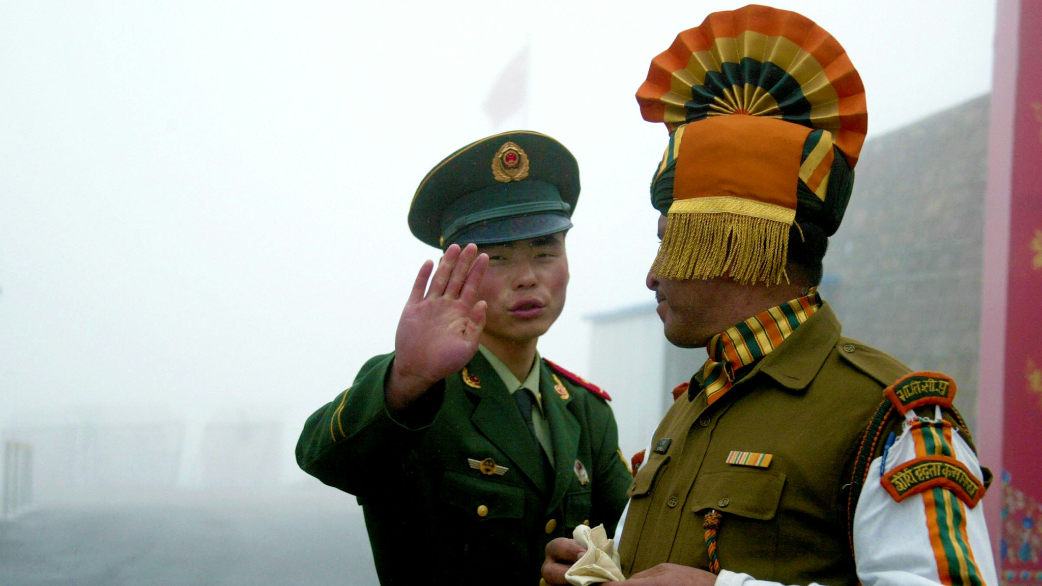 In this photograph taken on July 10, 2008, A Chinese soldier gestures as he stands near an Indian soldier on the Chinese side of the ancient Nathu La border crossing between India and China. When the two Asian giants opened the 4,500-metre-high (15,000 feet) pass in 2006 to improve ties dogged by a bitter war in 1962 that saw the route closed for 44 years, many on both sides hoped it would boost trade. Two years on, optimism has given way to despair as the flow of traders has shrunk to a trickle because of red tape, poor facilities and sub-standard roads in India's remote northeastern mountainous state of Sikkim.