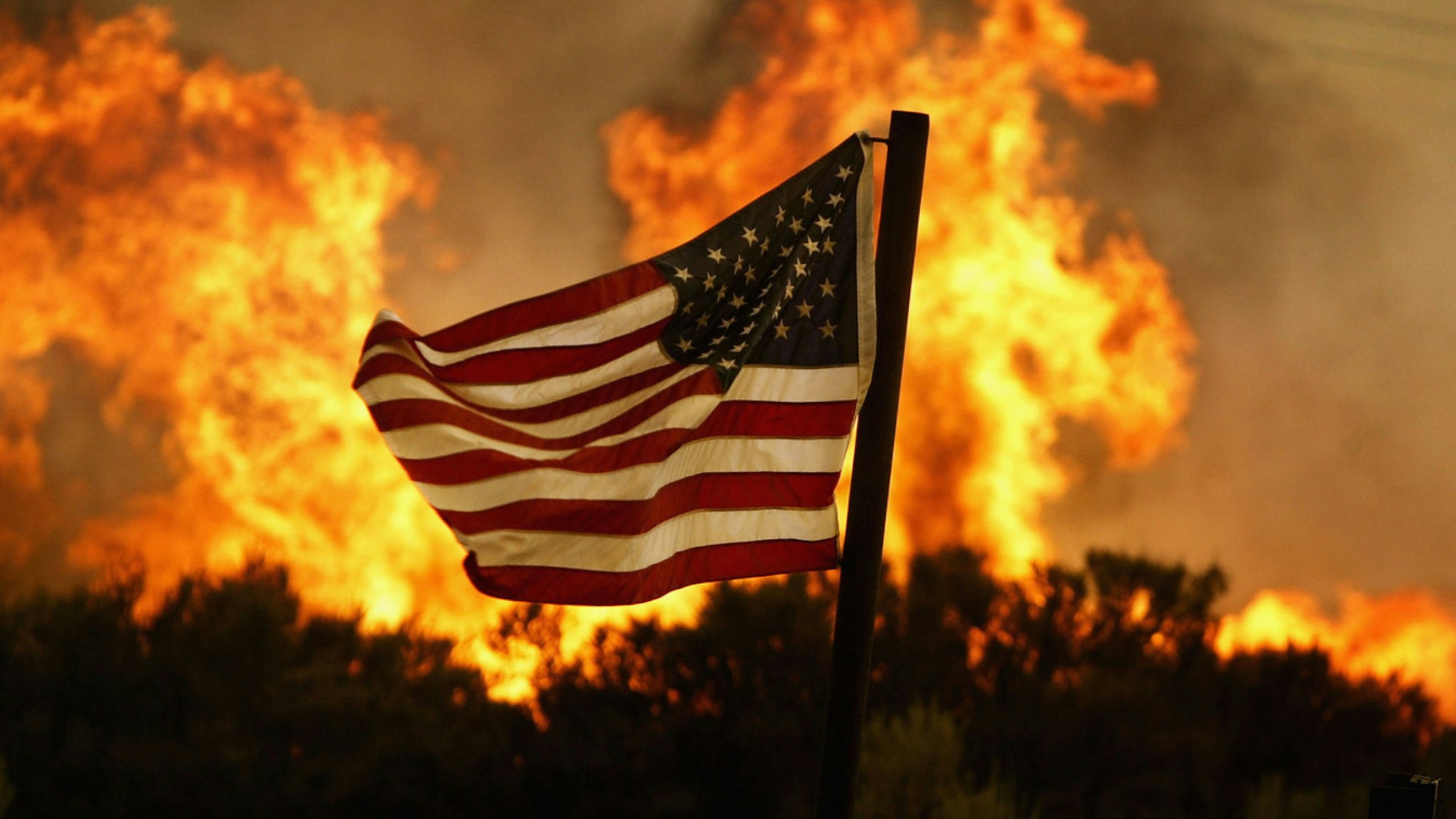 Flames approach an American flag at the Crown Fire on July 20, 2004 near Acton, California.