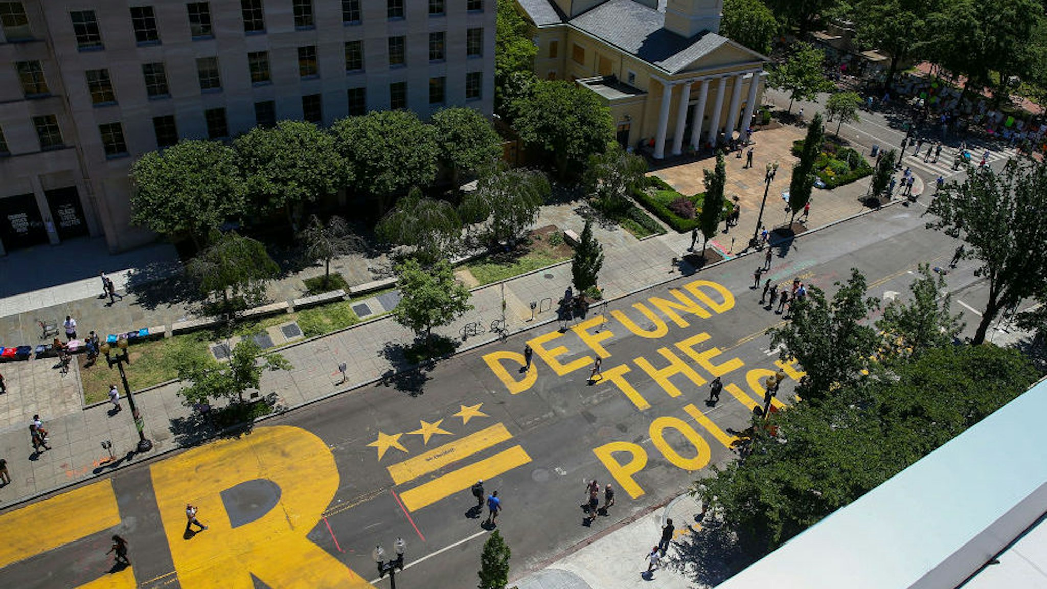 People walk down 16th street after ‚ÄúDefund The Police‚Äù was painted on the street near the White House on June 08, 2020 in Washington, DC. After days of protests in DC over the death of George Floyd, DC Mayor Muriel Bowser has renamed that section of 16th street "Black Lives Matter Plaza". (Photo by Tasos Katopodis/Getty Images)