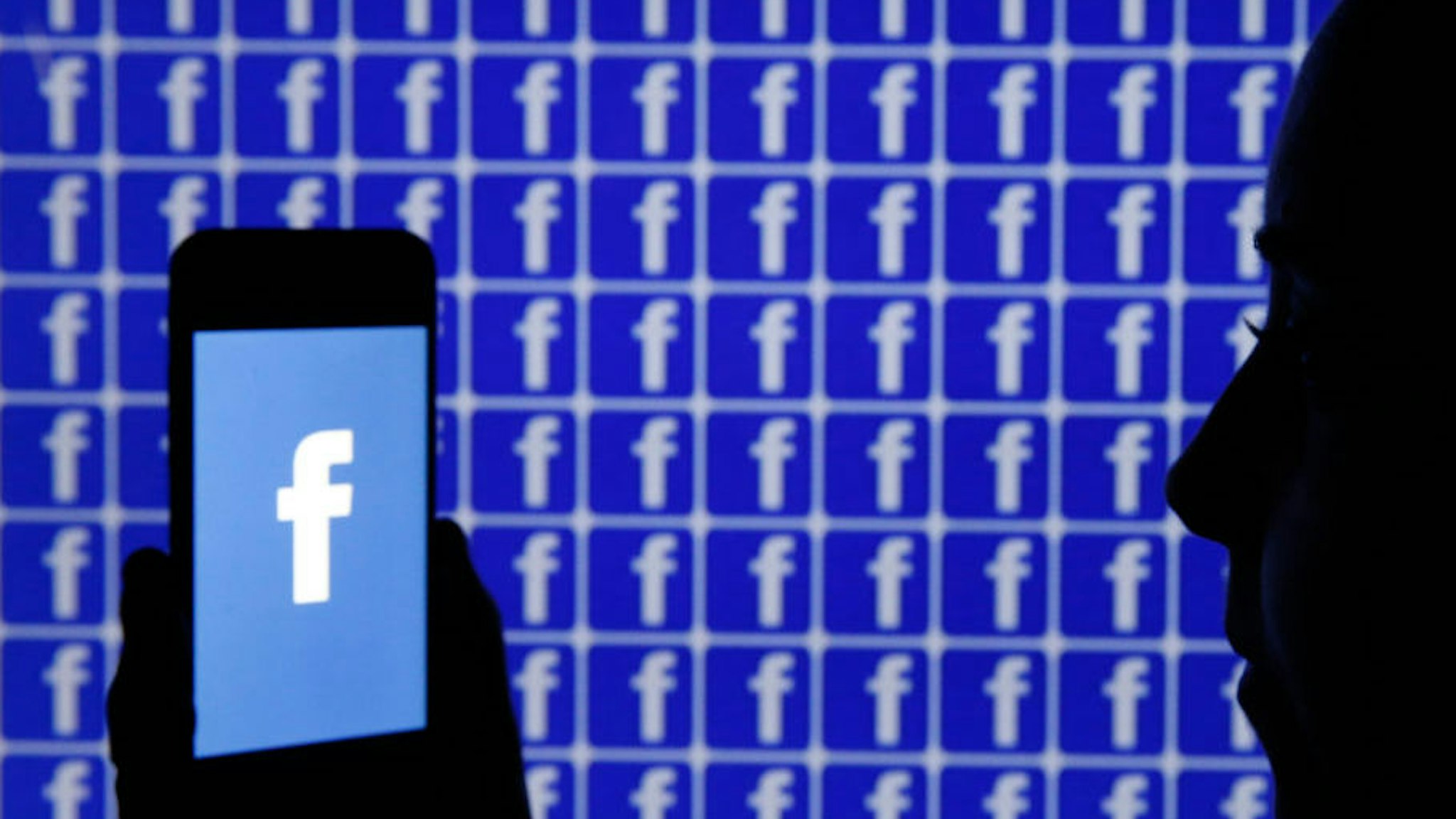 In this photo illustration, the Facebook logo is displayed on the screen of an iPhone in front of a TV screen displaying the Facebook logo on December 26, 2019 in Paris, France. The American company Facebook created in 2004 by Mark Zuckerberg builds technologies that give people the power to connect with friends and family, find communities and grow businesses. (Photo by Chesnot/Getty Images)