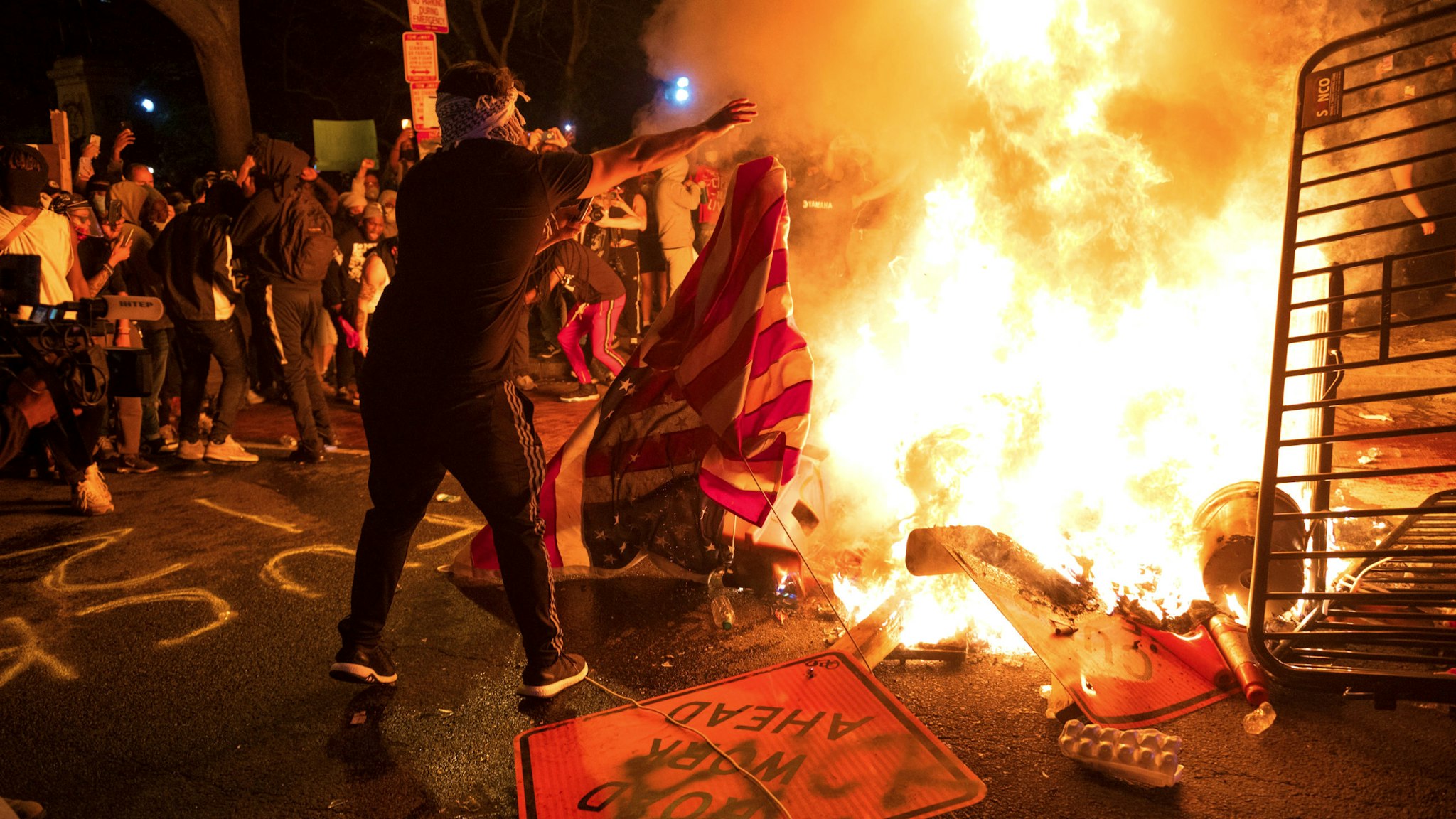 A protester throws a US flag into a burning barricade during a demonstration against the death of George Floyd near the White House on May 31, 2020 in Washington, DC. - Thousands of National Guard troops patrolled major US cities after five consecutive nights of protests over racism and police brutality that boiled over into arson and looting, sending shock waves through the country. The death Monday of an unarmed black man, George Floyd, at the hands of police in Minneapolis ignited this latest wave of outrage in the US over law enforcement's repeated use of lethal force against African Americans -- this one like others before captured on cellphone video.