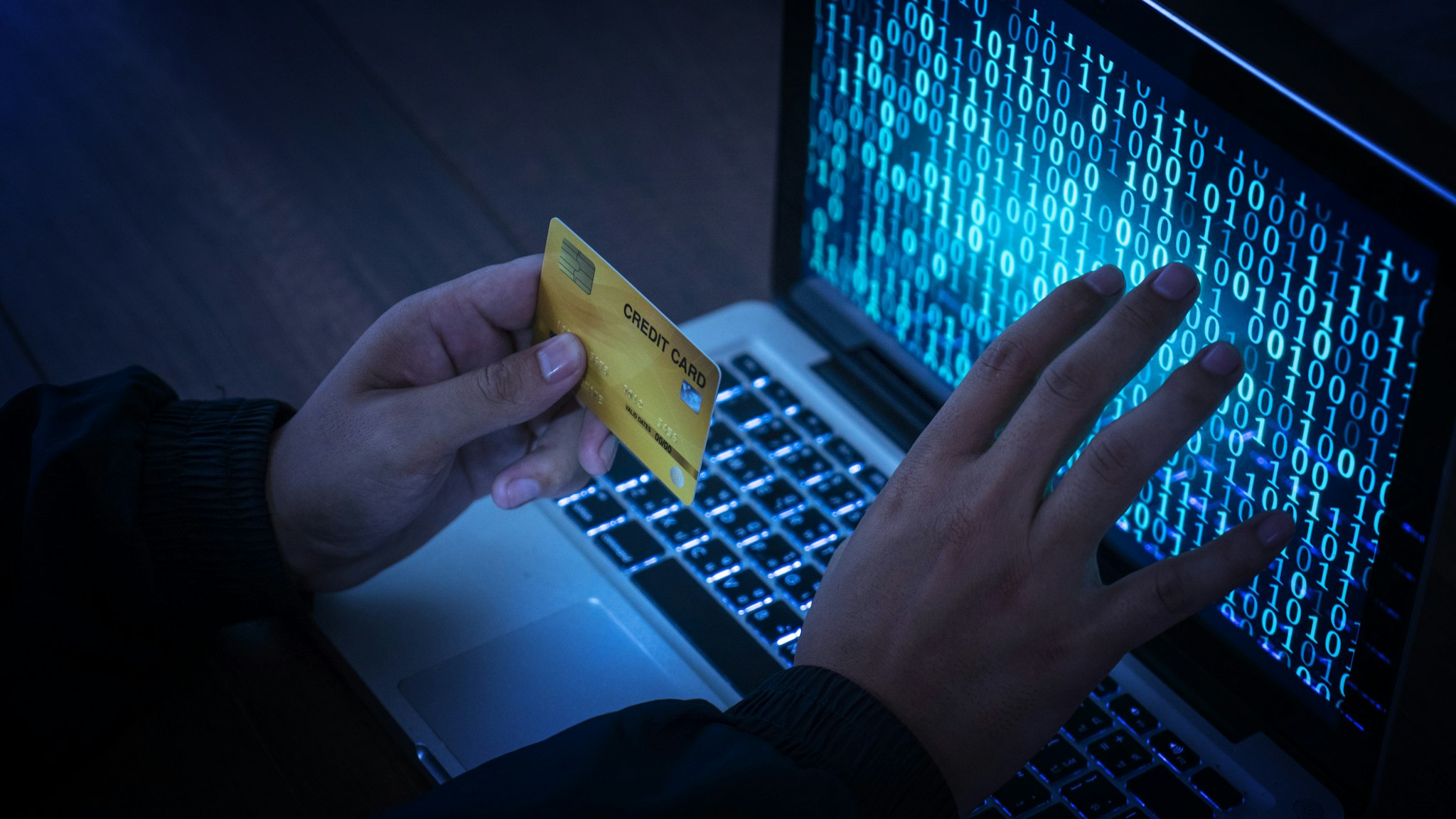Hands of anonymous hackers holding credit card - stock photo