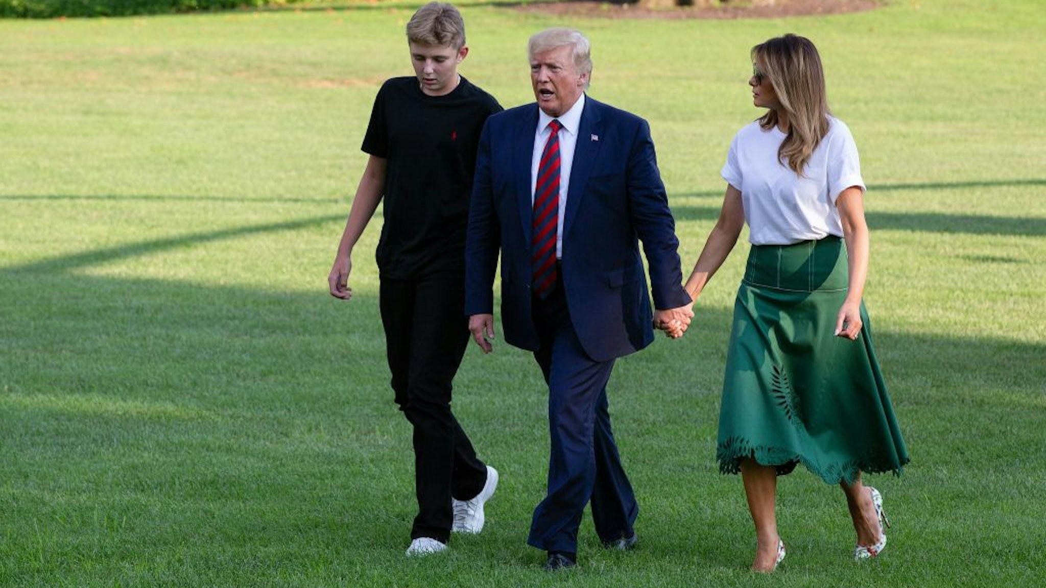 US President Donald Trump (C) First Lady Melania Trump (R) and their son Barron Trump (L) return to the White House after two weeks spent at Trump's golf club in New Jersey on August 18, 2019 in Washington, DC.