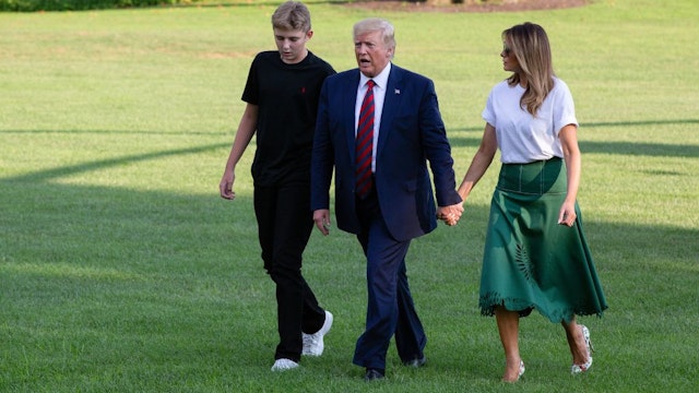 US President Donald Trump (C) First Lady Melania Trump (R) and their son Barron Trump (L) return to the White House after two weeks spent at Trump's golf club in New Jersey on August 18, 2019 in Washington, DC.
