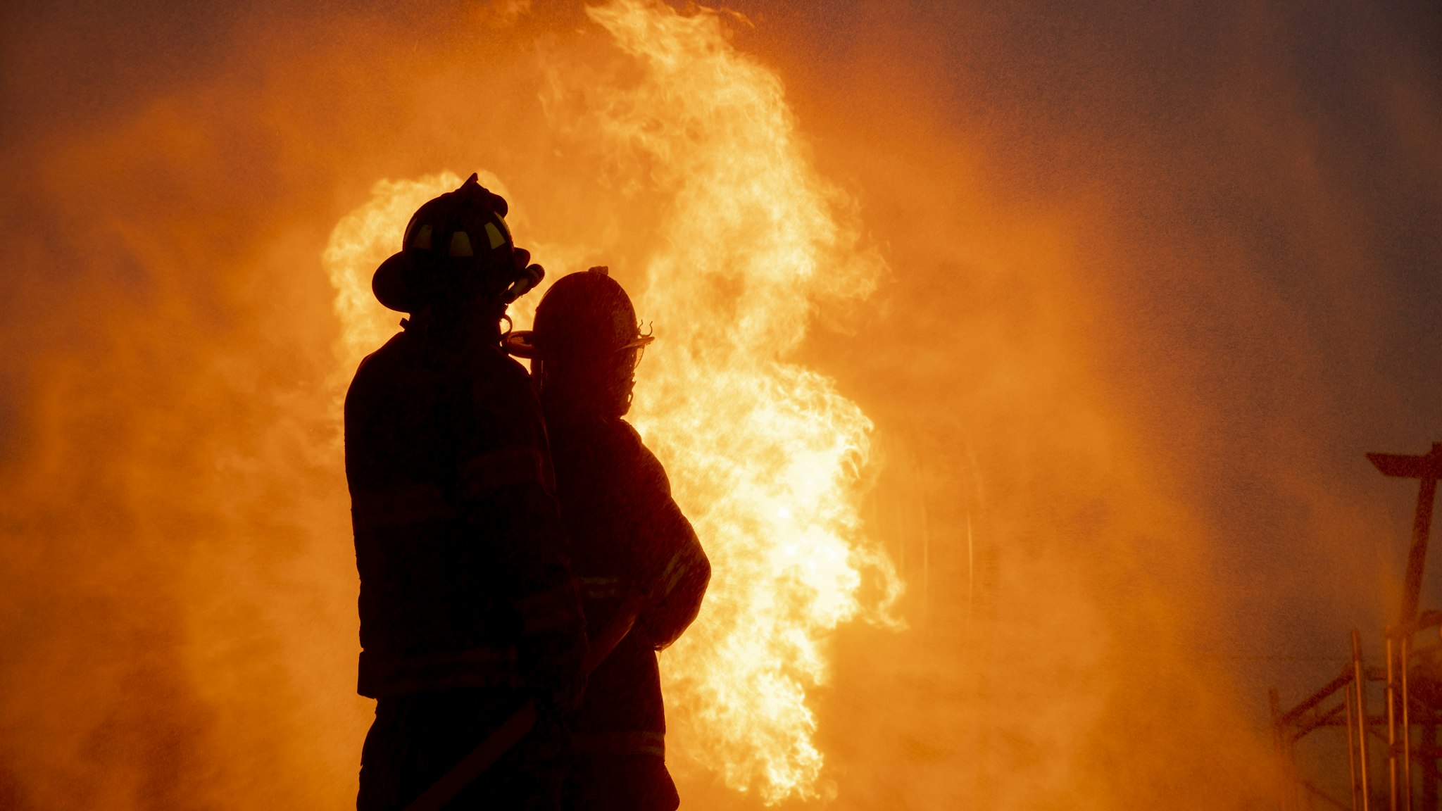 Silhouette of two firefighter in front of the big fire, Fire insurance concept - stock photo