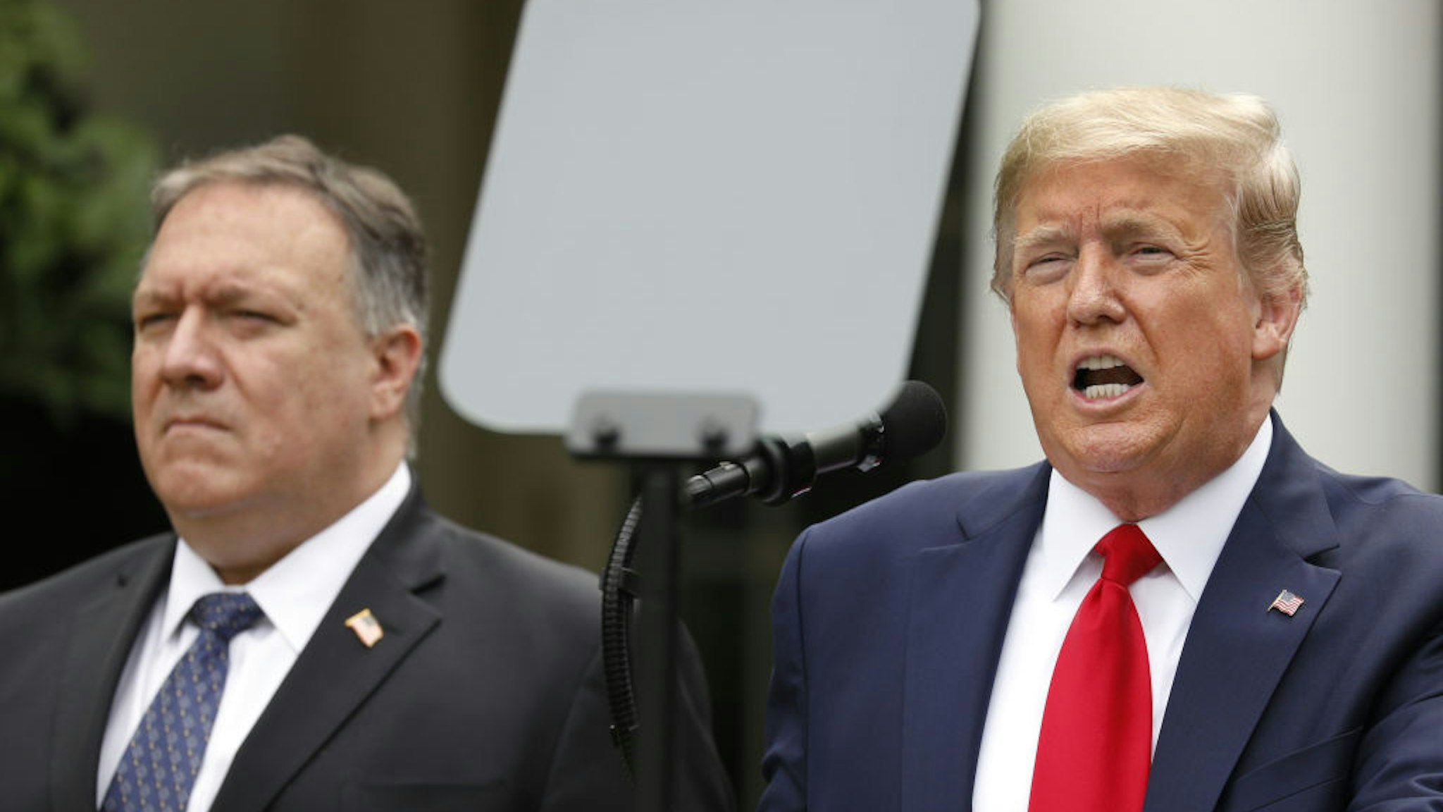 U.S. President Donald Trump speaks as Mike Pompeo, U.S. secretary of state, left, listens during a news conference in the Rose Garden of the White House in Washington, D.C., U.S., on Friday, May 29, 2020.