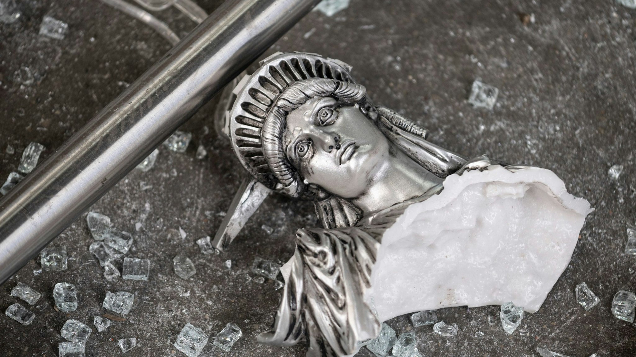 TOPSHOT - A broken Statue of Liberty figure is seen between glass shatters outside a looted souvenir shop after a night of protest over the death of an African-American man George Floyd in Minneapolis on June 2, 2020 in Manhattan in New York City. - New York's mayor Bill de Blasio yesterday declared a city curfew from 11:00 pm to 5:00 am, as sometimes violent anti-racism protests roil communities nationwide. Saying that "we support peaceful protest," De Blasio tweeted he had made the decision in consultation with the state's governor Andrew Cuomo, following the lead of many large US cities that instituted curfews in a bid to clamp down on violence and looting. (Photo by Johannes EISELE / AFP) (Photo by JOHANNES EISELE/AFP via