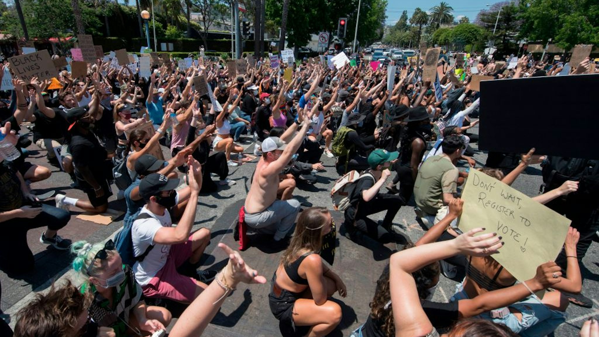 Demonstrators take a knee and put their hands up in front of officers from the Sheriff's Department as they protest the death of George Floyd, in West Hollywood, California on June 3, 2020.