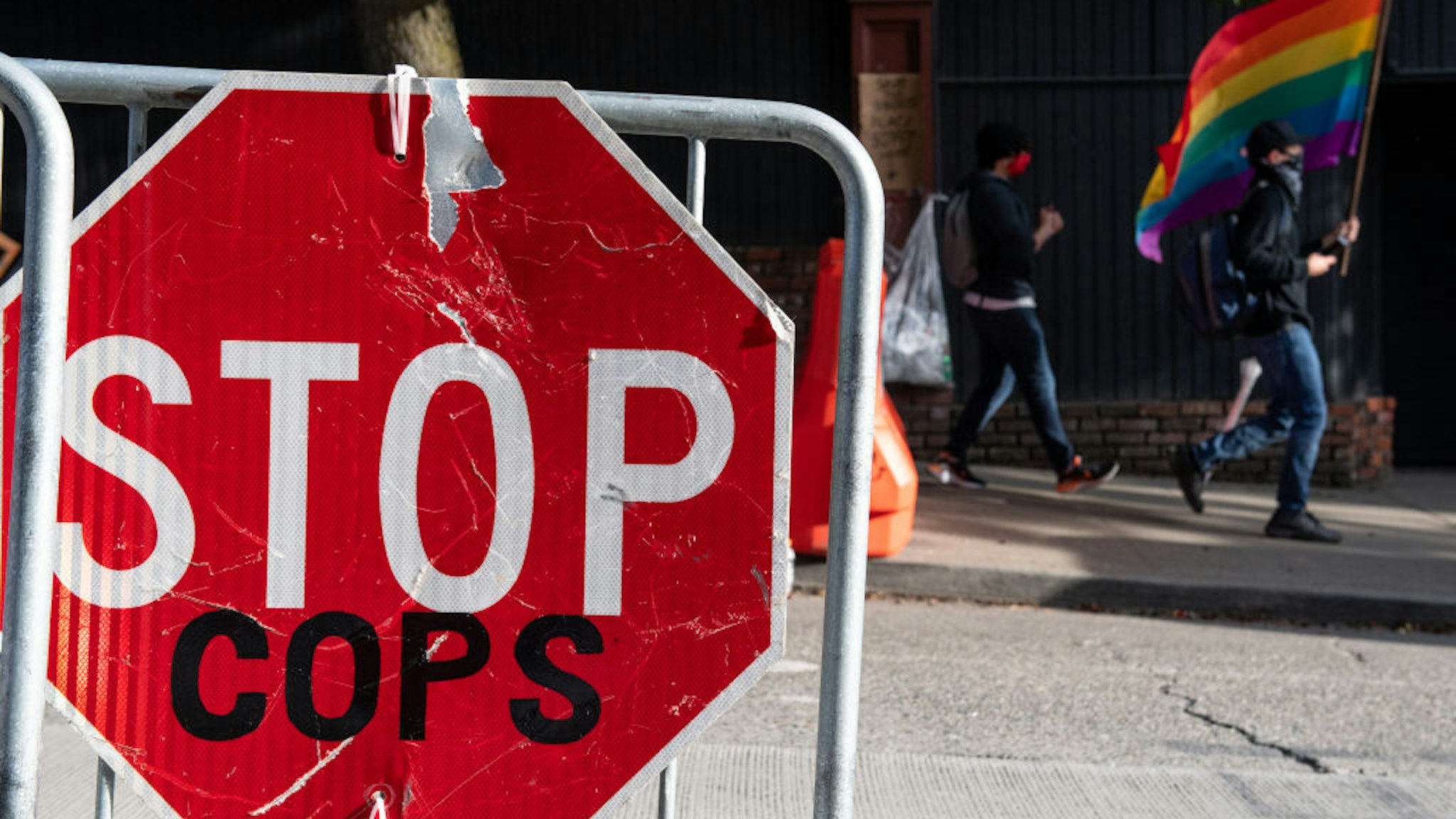 A man walks past a stop sign reading stop cops inside the Capitol Hill Organized Protest formerly known as the Capitol Hill Autonomous Zone in Seattle, Washington on June 14, 2020.