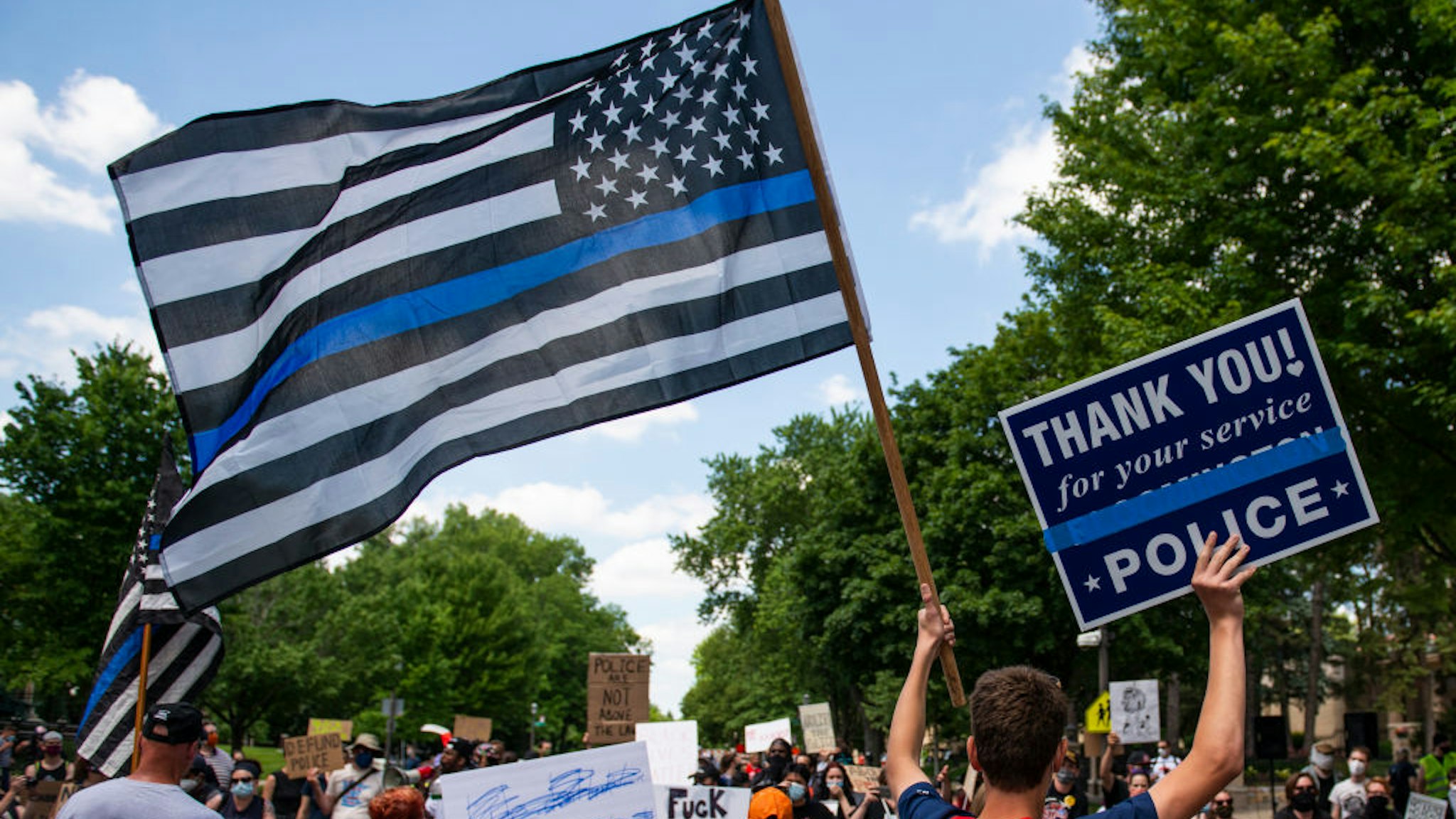 A demonstrator holds a "Thin Blue Line" flag and a sign in support of police during a protest outside the Governors Mansion on June 27, 2020 in St Paul, Minnesota.