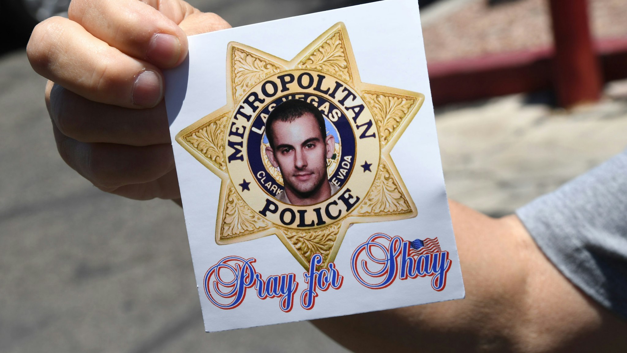 LAS VEGAS, NEVADA - JUNE 11: A woman displays a sticker she received at an Injured Police Officers Fund (IPOF) of Nevada "Shay Day" fundraiser for Las Vegas Metropolitan Police Department Officer Shay Mikalonis at the Sahara West Urgent Care & Wellness parking lot on June 11, 2020 in Las Vegas, Nevada. Mikalonis was shot in the head during an anti-racism protest on the Las Vegas Strip in the wake of George Floyd's death on June 1. He is on a ventilator and is listed in critical condition at University Medical Center of Southern Nevada. Edgar Samaniego, 20, who was not part of the protest, was arrested for the shooting and is facing charges including attempted murder. (Photo by Ethan Miller/Getty Images)
