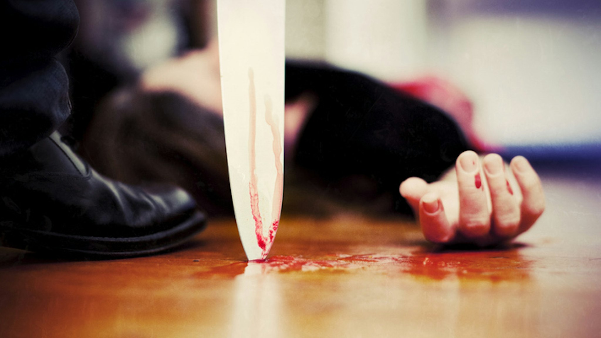"Close up on a bloody knife planted on a wooden floor, a killing scene"