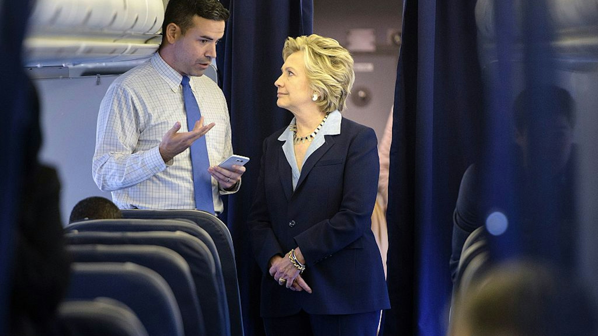 Democratic presidential nominee Hillary Clinton looks at a smart phone with national press secretary Brian Fallon on her plane at Westchester County Airport October 3, 2016 in White Plains, New York.