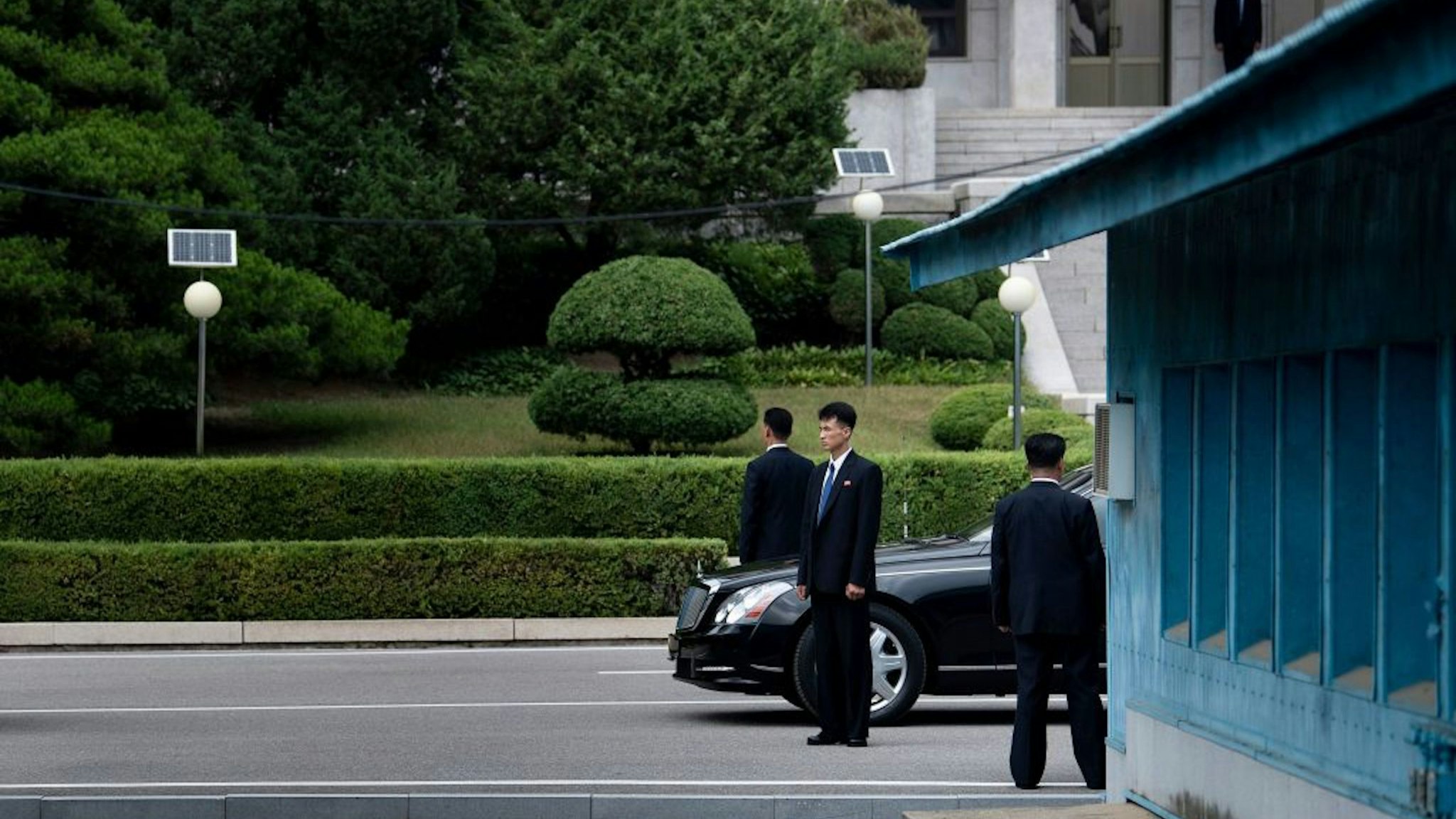 Members of North Korean security stands guard near a North Korean motorcade while US President Donald Trump and North Korea's leader Kim Jong-un meet in the Demilitarized Zone(DMZ) on June 30, 2019.
