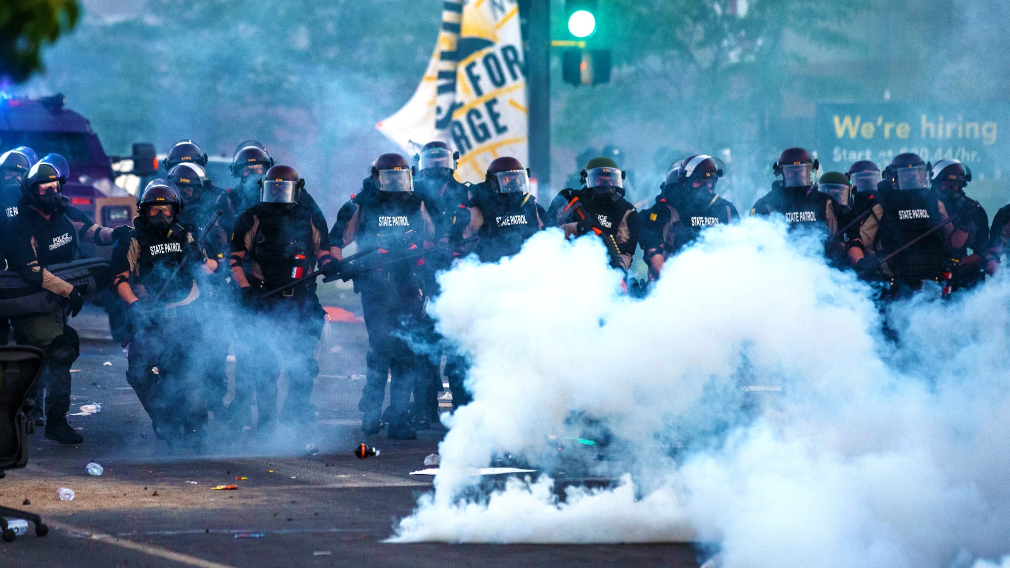 Smoke rises near a row of police in riot gear near the 5th police precinct during a demonstration to call for justice for George Floyd, a black man who died while in custody of the Minneapolis police, on May 30, 2020 in Minneapolis, Minnesota. - Clashes broke out and major cities imposed curfews as America began another night of unrest Saturday with angry demonstrators ignoring warnings from President Donald Trump that his government would stop violent protests over police brutality "cold."