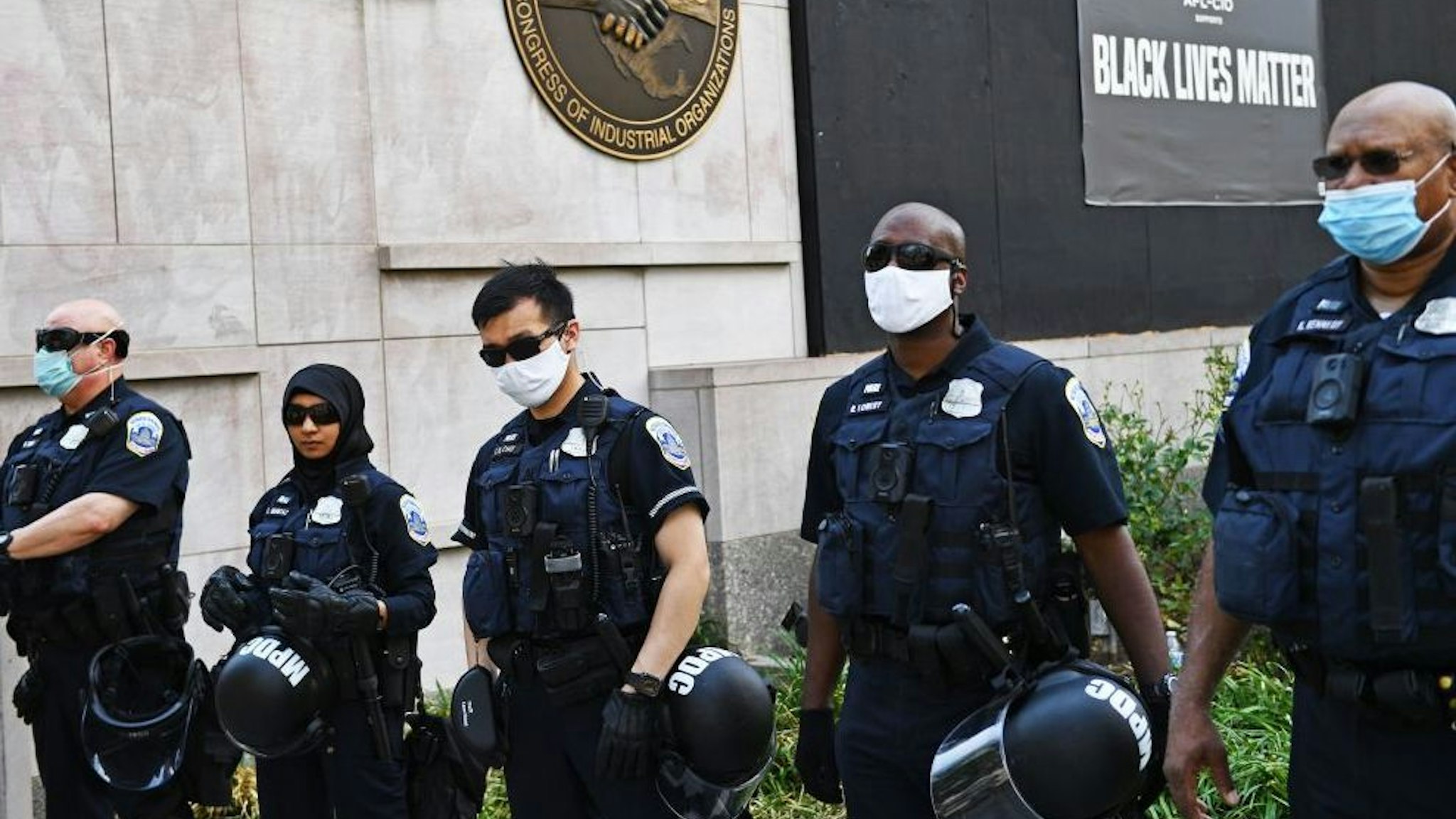 A line of police officers stand at the readyd with riot gear as they form a security perimeter on 16th St. NW near Black Lives Matter Plazza and Lafayette Square near the White House in Washington, DC on June 23, 2020. - US President Trump on his way to Arizona warned that protesters who attempted to establish an "autonomous zone" in the US capital would be met with "serious force," following a night of protests at Lafayette Square where a crowd of protestors tried to topple the statue of Andrew Jackson. (Photo by Brendan Smialowski / AFP)