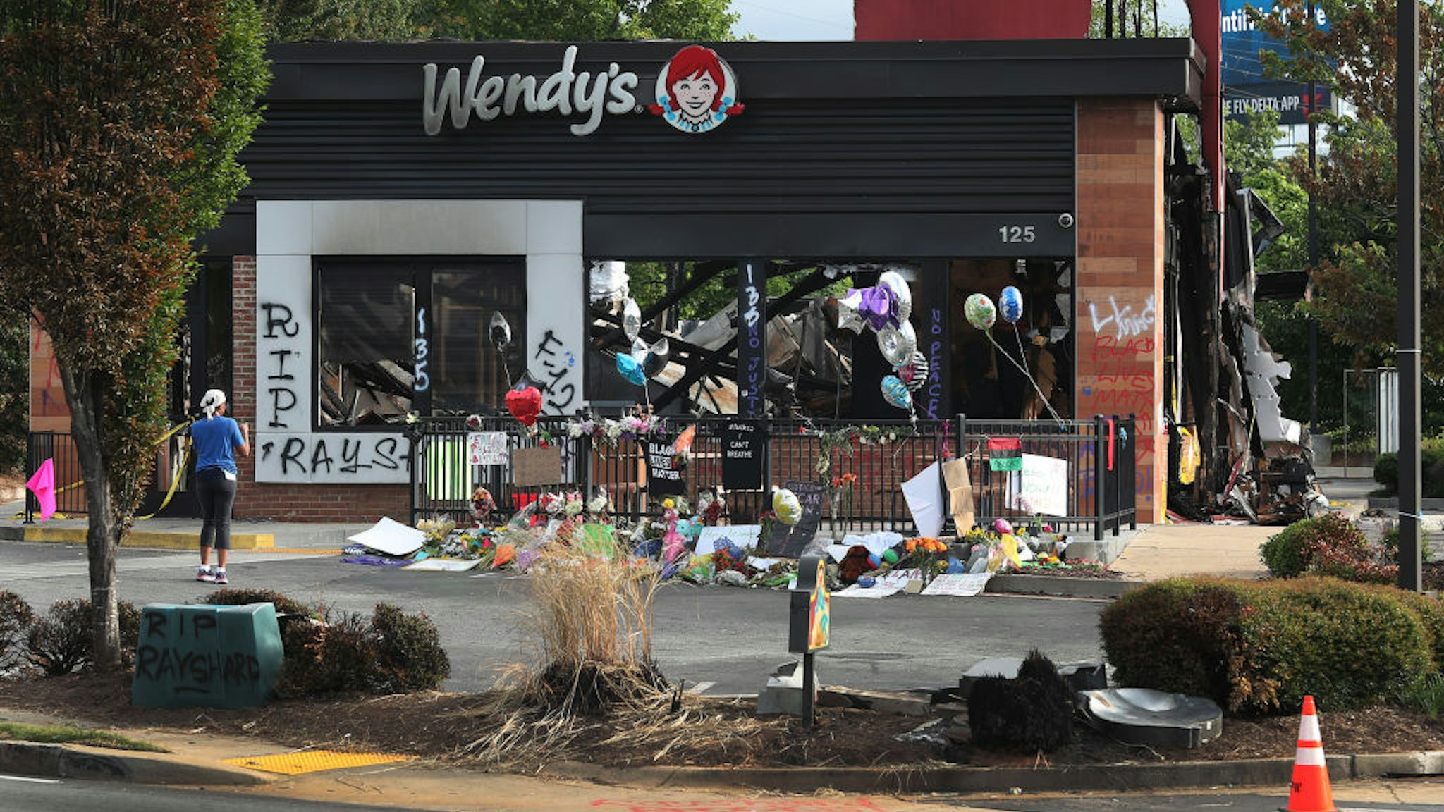 ATLANTA, GEORGIA - JUNE 17: People visit the memorial setup outside the Wendy's restaurant that was set on fire by demonstrators after Rayshard Brooks was killed on June 17, 2020 in Atlanta, Georgia. The site has become a place of remembrance for Mr. Brooks, who was killed by police while fleeing after a struggle during a field sobriety test in the Wendy's parking lot. (Photo by Joe Raedle/Getty Images)