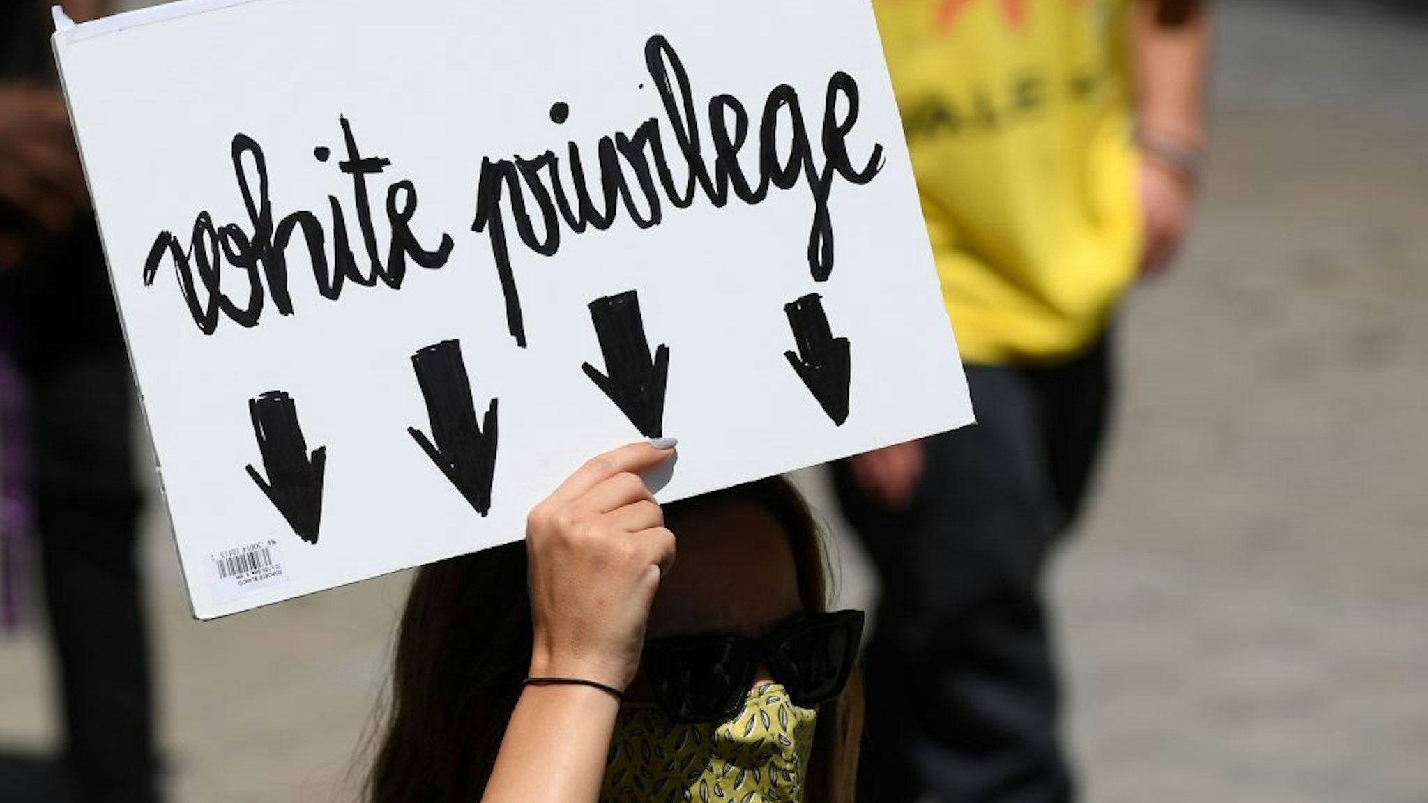 A woman holds a placard reading "White privilege" during a demonstration on June 14, 2020, in Barcelona, as part of the worldwide protests against racism and police brutality. - The protests are part of a worldwide movement following the killing in the United States of African-American man George Floyd who died after a white policeman knelt on his neck for several minutes. (Photo by Josep LAGO / AFP)