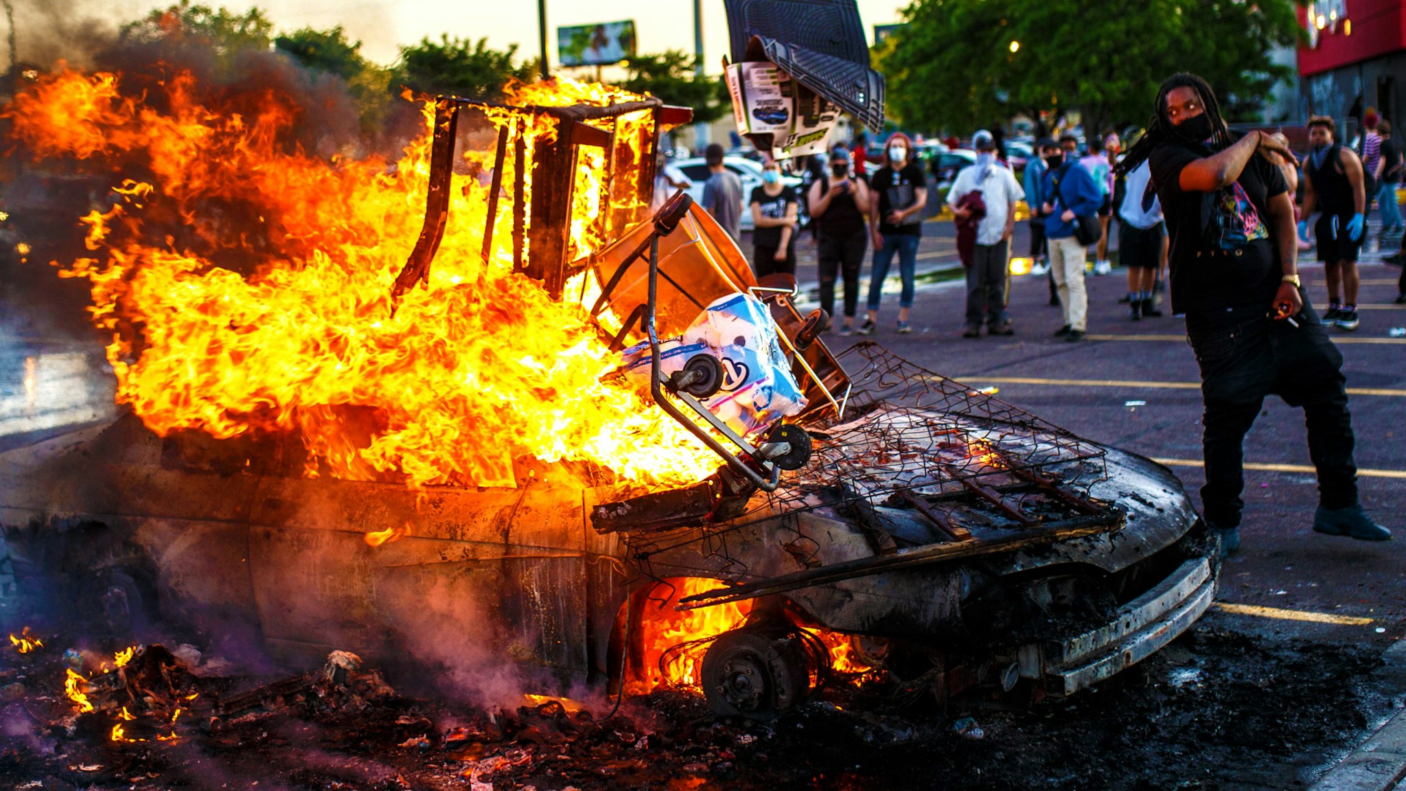 Protesters throw objects into a fire outside a Target store near the Third Police Precinct on May 28, 2020 in Minneapolis, Minnesota, during a demonstration over the death of George Floyd. - A police precinct in Minnesota went up in flames late on May 28 in a third day of demonstrations as the so-called Twin Cities of Minneapolis and St. Paul seethed over the shocking police killing of Floyd. The precinct, which police had abandoned, burned after a group of protesters pushed through barriers around the building, breaking windows and chanting slogans. A much larger crowd demonstrated as the building went up in flames.