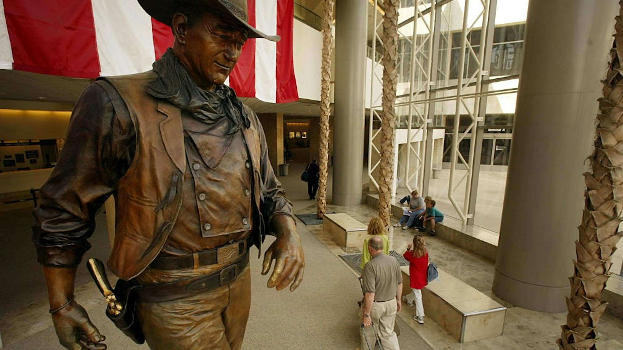 (Santa Ana) Passengers file by the statue of John Wayne at John Wayne Airport. There s a proposal floating around to change the name of John Wayne Airport to the O.C. What do people have to say? Photo taken Tuesday June 8, 2004. (Photo by